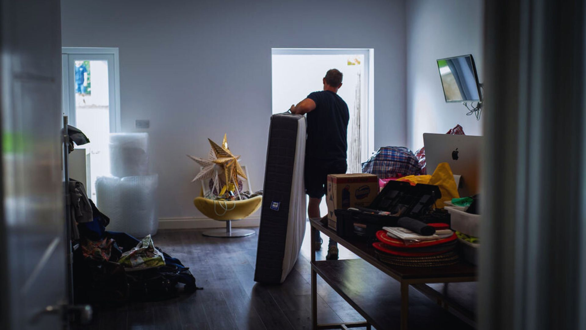 Man rearranging furniture in a room, lifting a chair and preparing to place it in a different location.