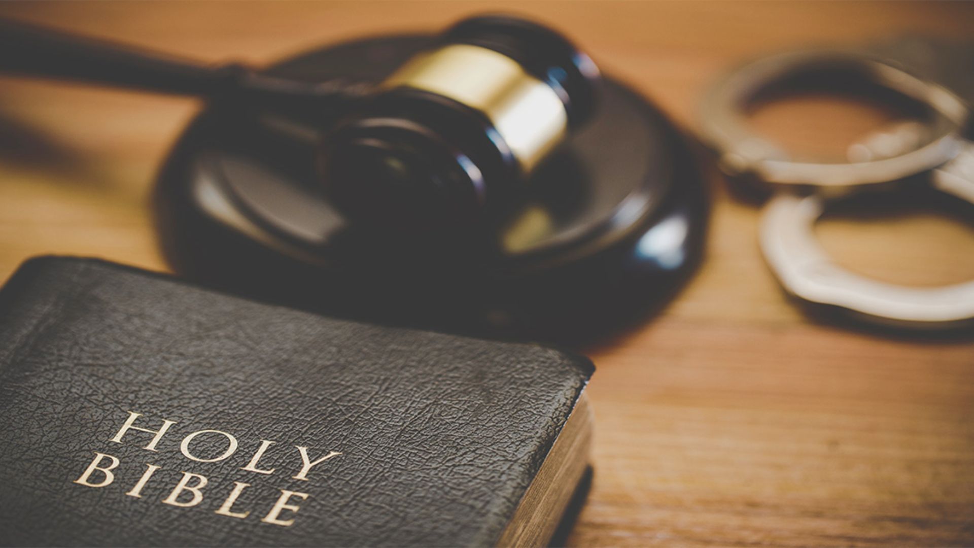 A Bible placed next to a pair of handcuffs, symbolizing the contrast between faith and confinement.