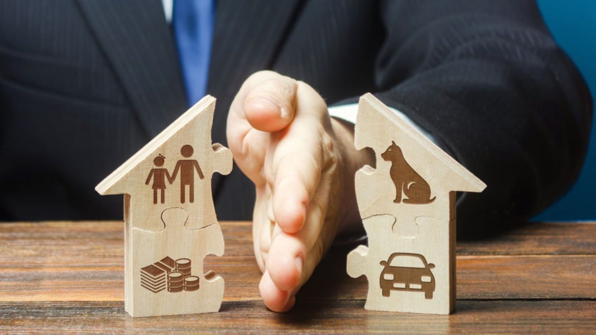 Businessman holds a puzzle piece shaped like a house, symbolizing family and a dog, on a wooden table.