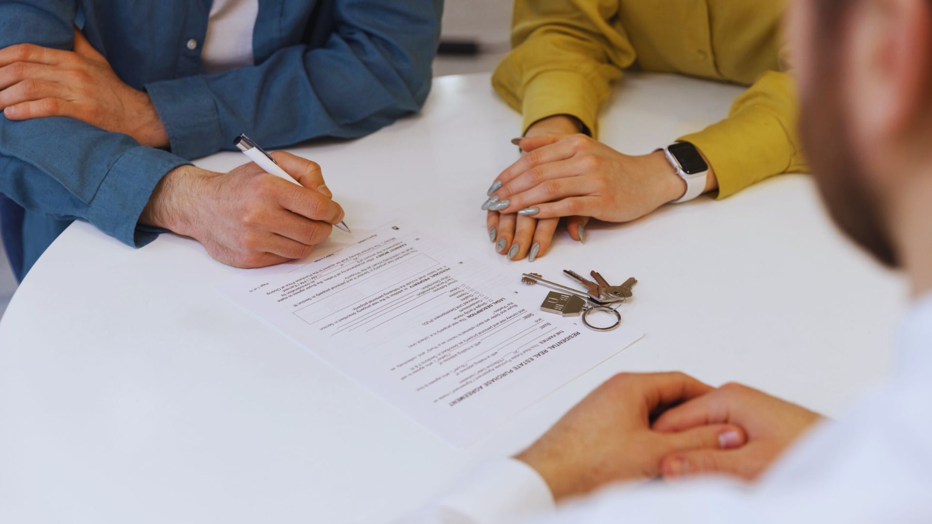A couple signing a contract while holding a key, symbolizing the purchase of a new home or property.
