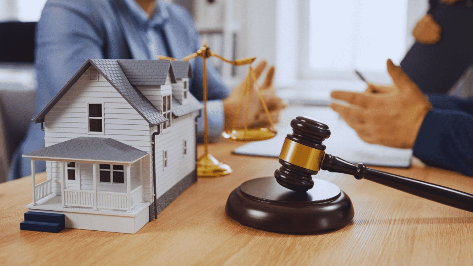 A judge's gavel rests beside a model house on a table, symbolizing legal matters related to real estate.