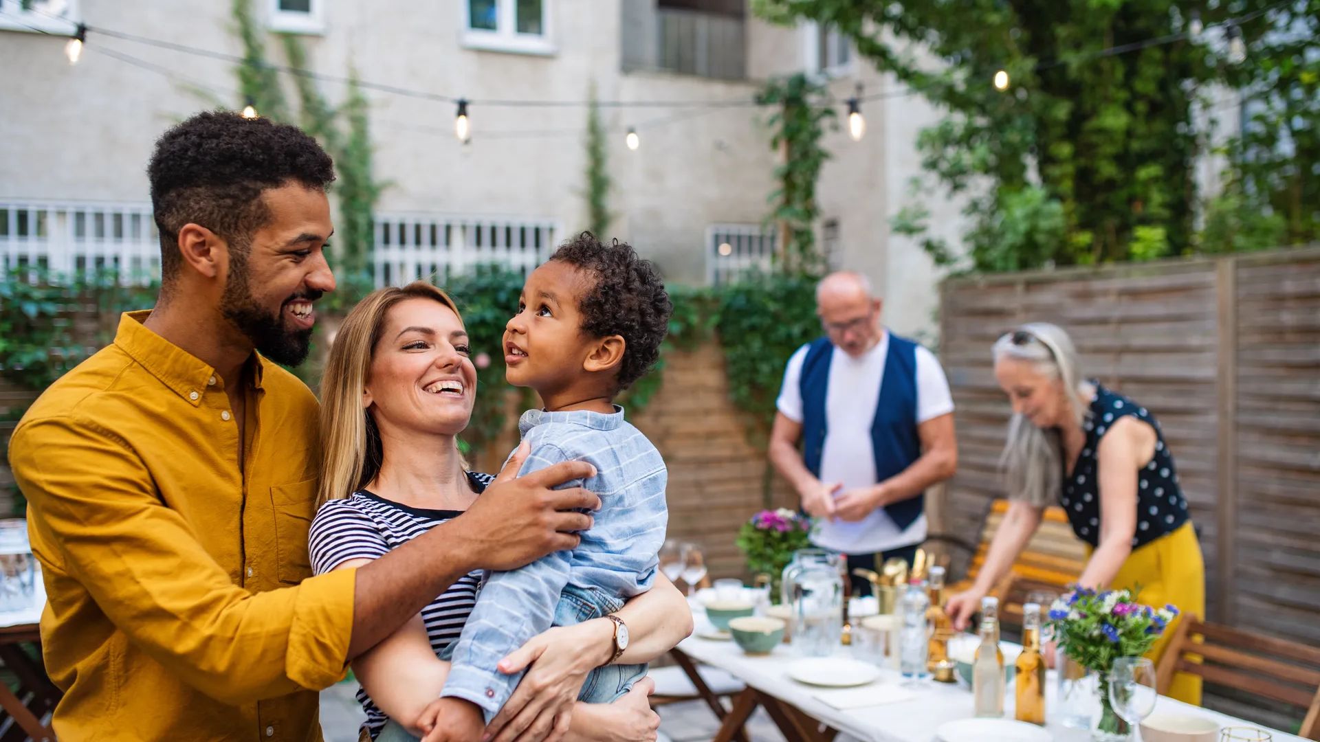 A family gathered around a picnic table, enjoying a meal together outdoors under a clear blue sky.