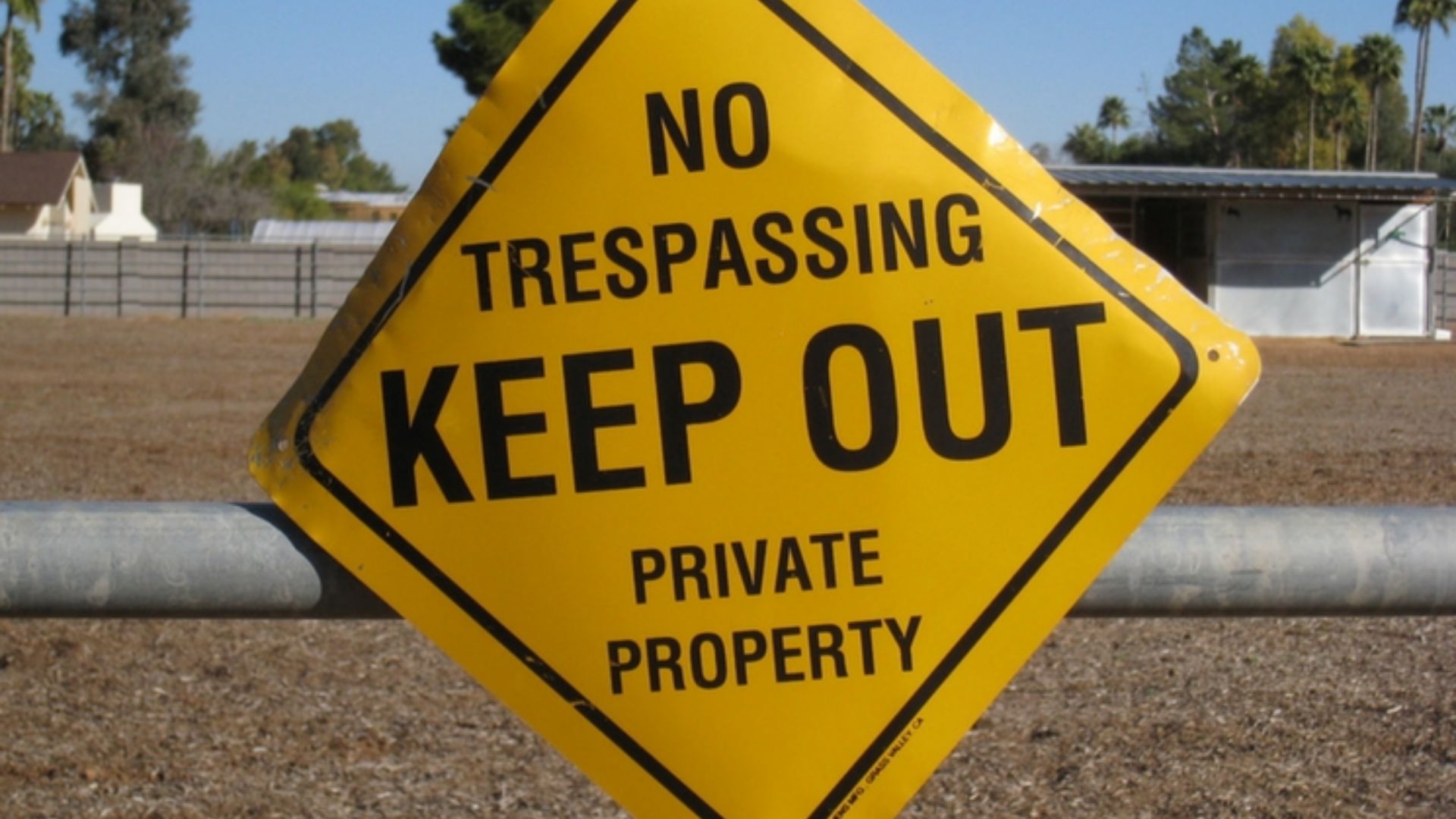 A yellow no trespassing sign stating "Keep Out" on private property.