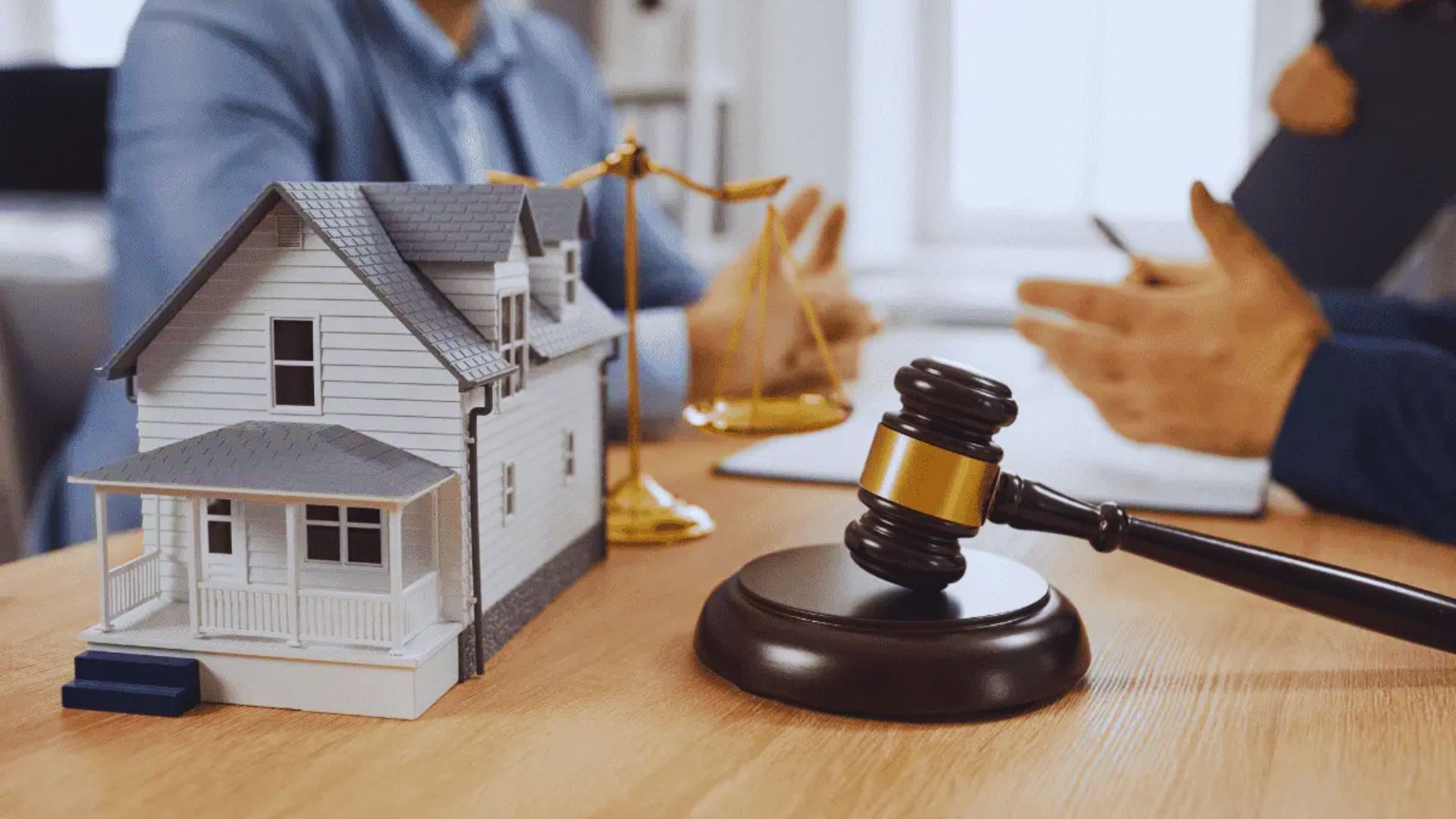 A judge's gavel rests beside a model house on a table, symbolizing legal matters related to real estate.
