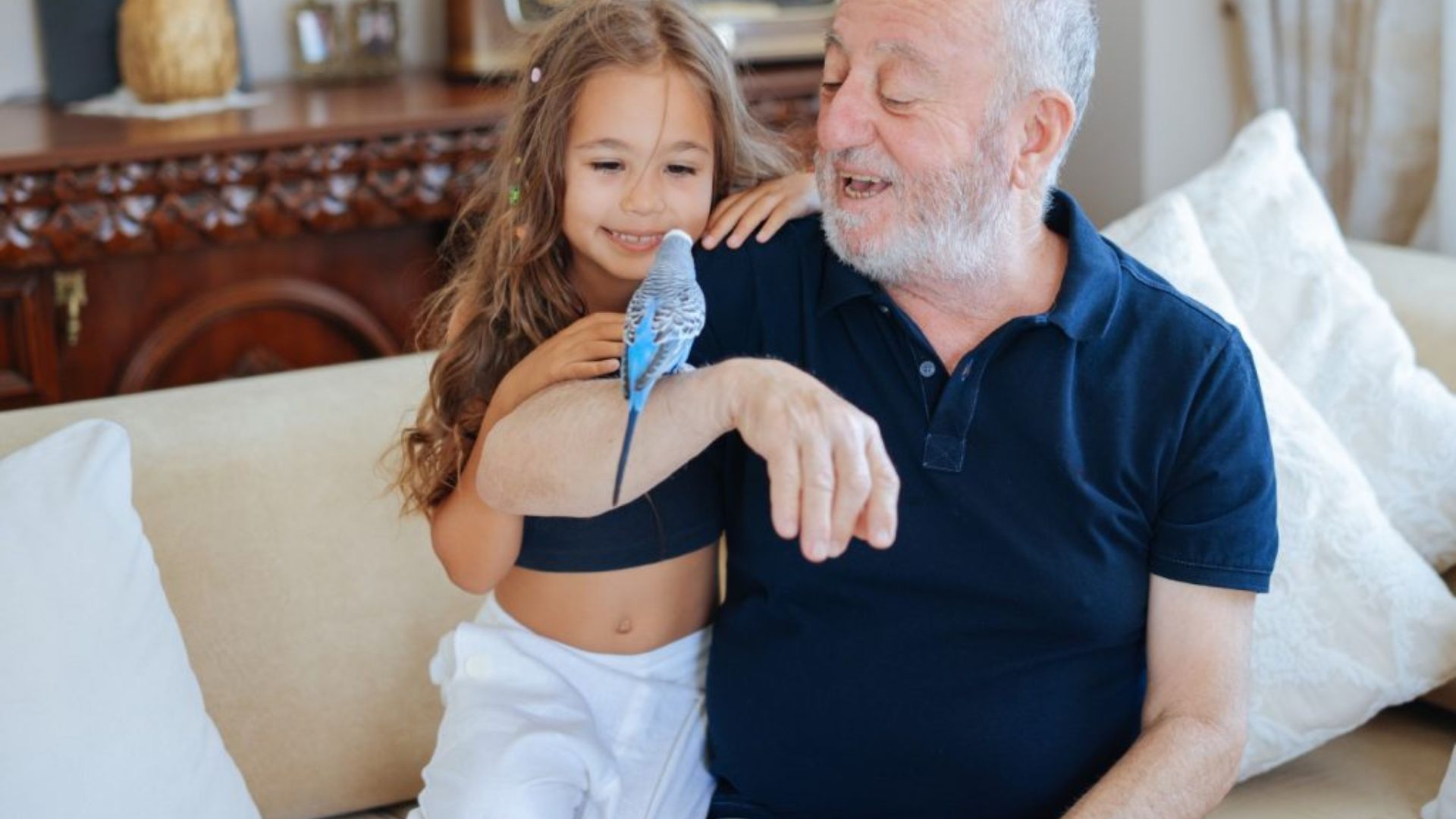 An older man and a young girl sitting together on a couch, sharing a moment of joy and companionship.