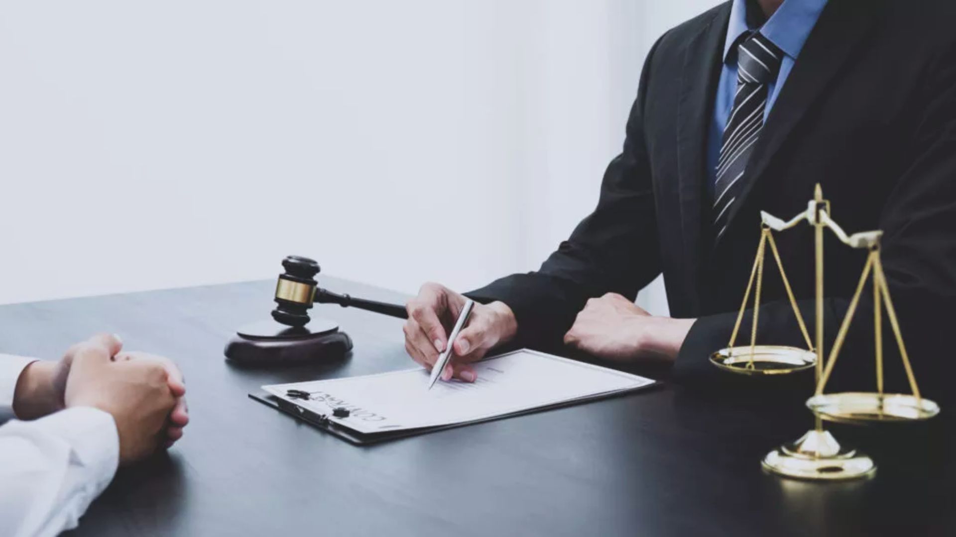A lawyer and a judge are seated at a desk, engaged in a discussion in a courtroom setting.