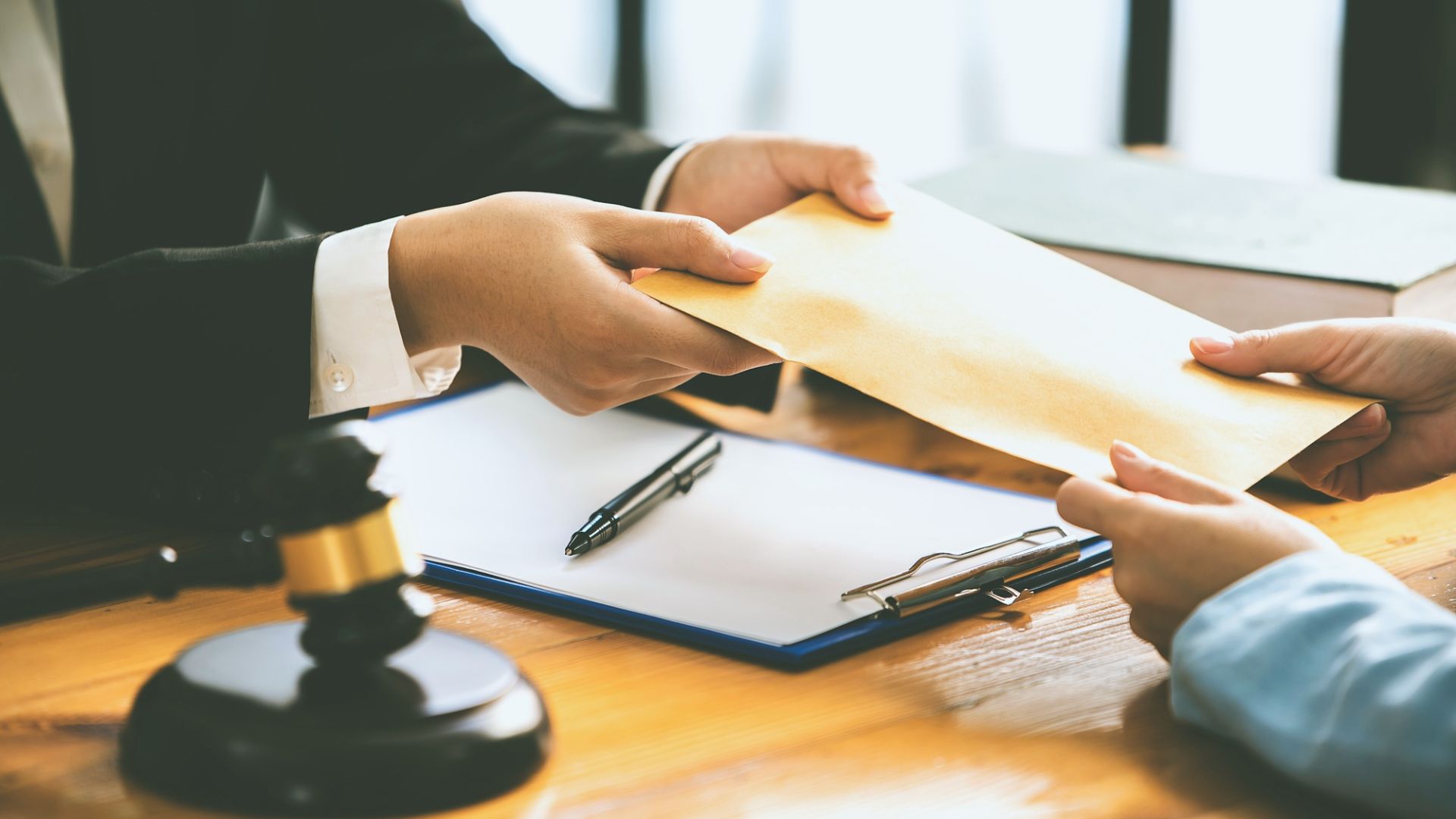 A lawyer hands a legal document to a client in a professional office setting.