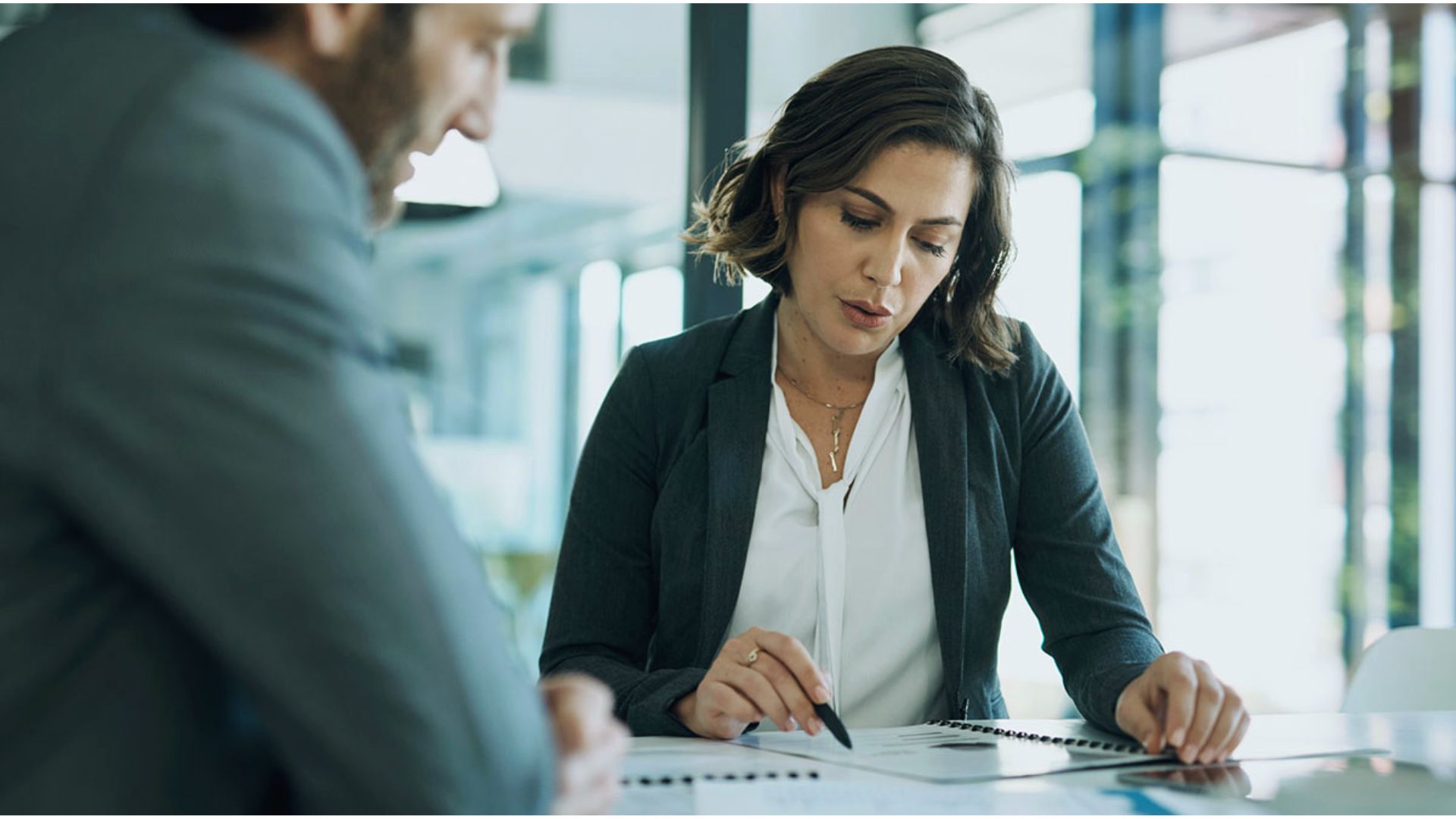 A woman and a man in business attire collaborate on a project at a modern office workspace.