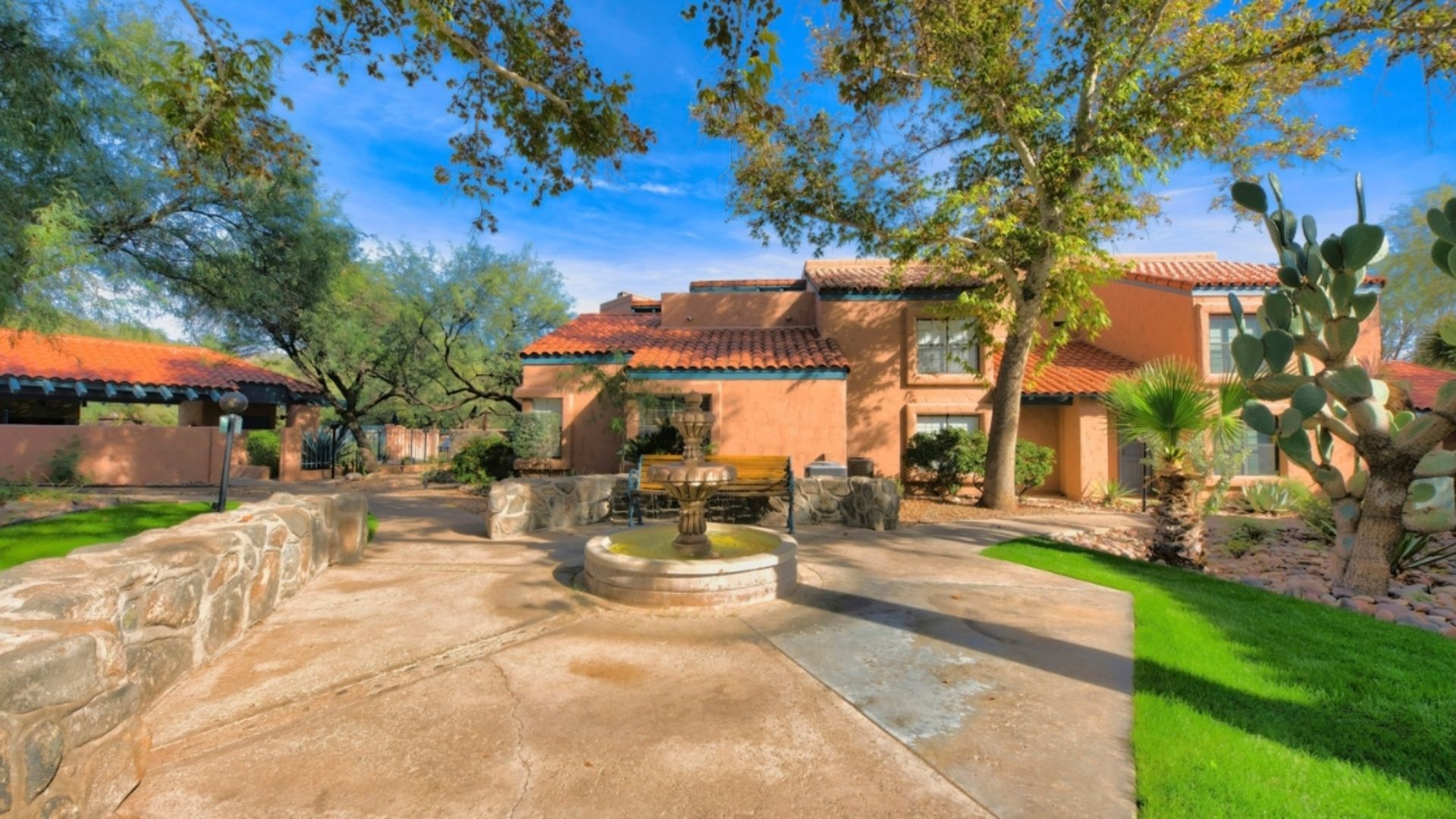 A charming home featuring a decorative fountain in the front yard, surrounded by lush greenery.