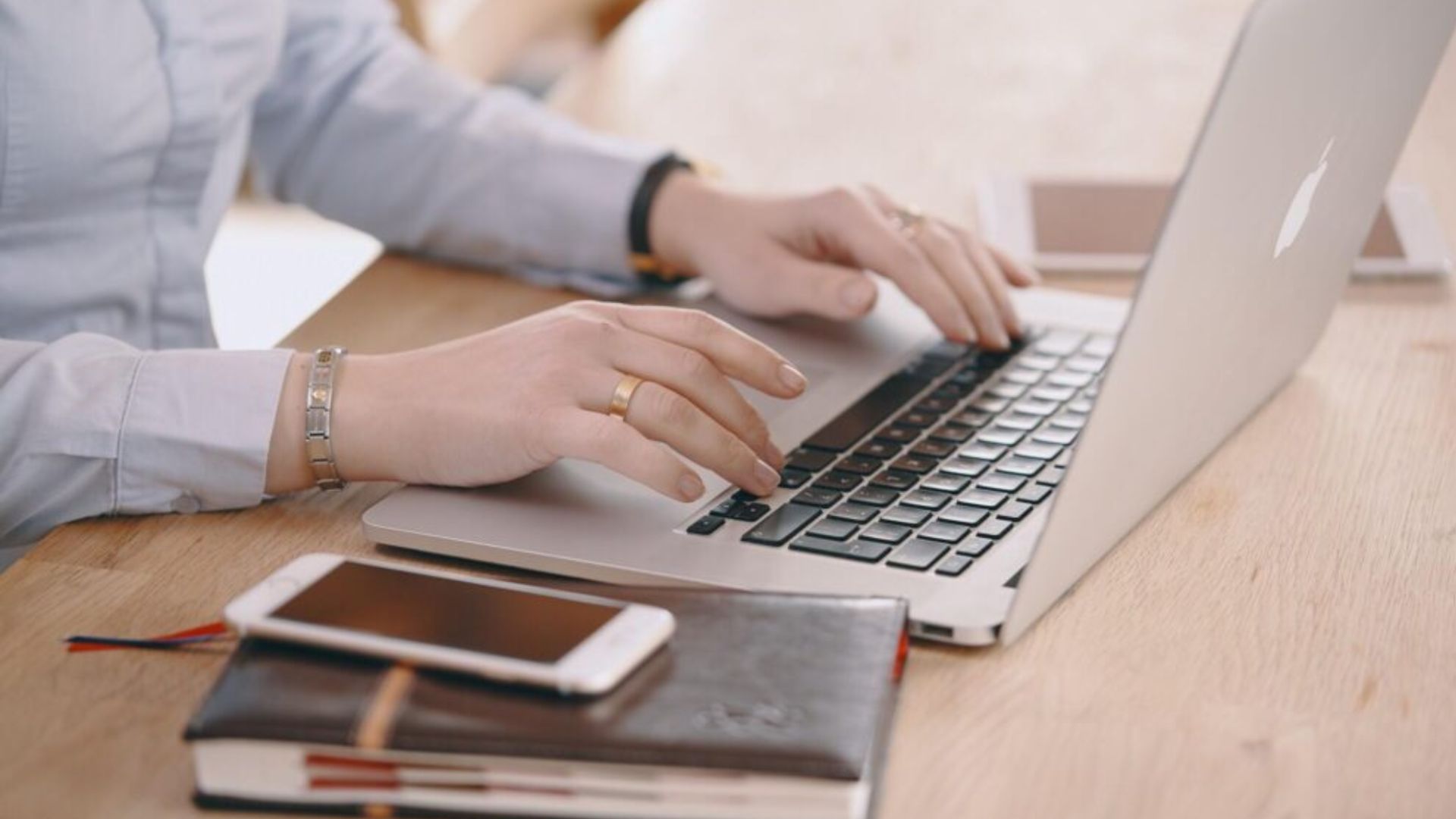A person focused on typing on a laptop computer, with hands positioned on the keyboard.
