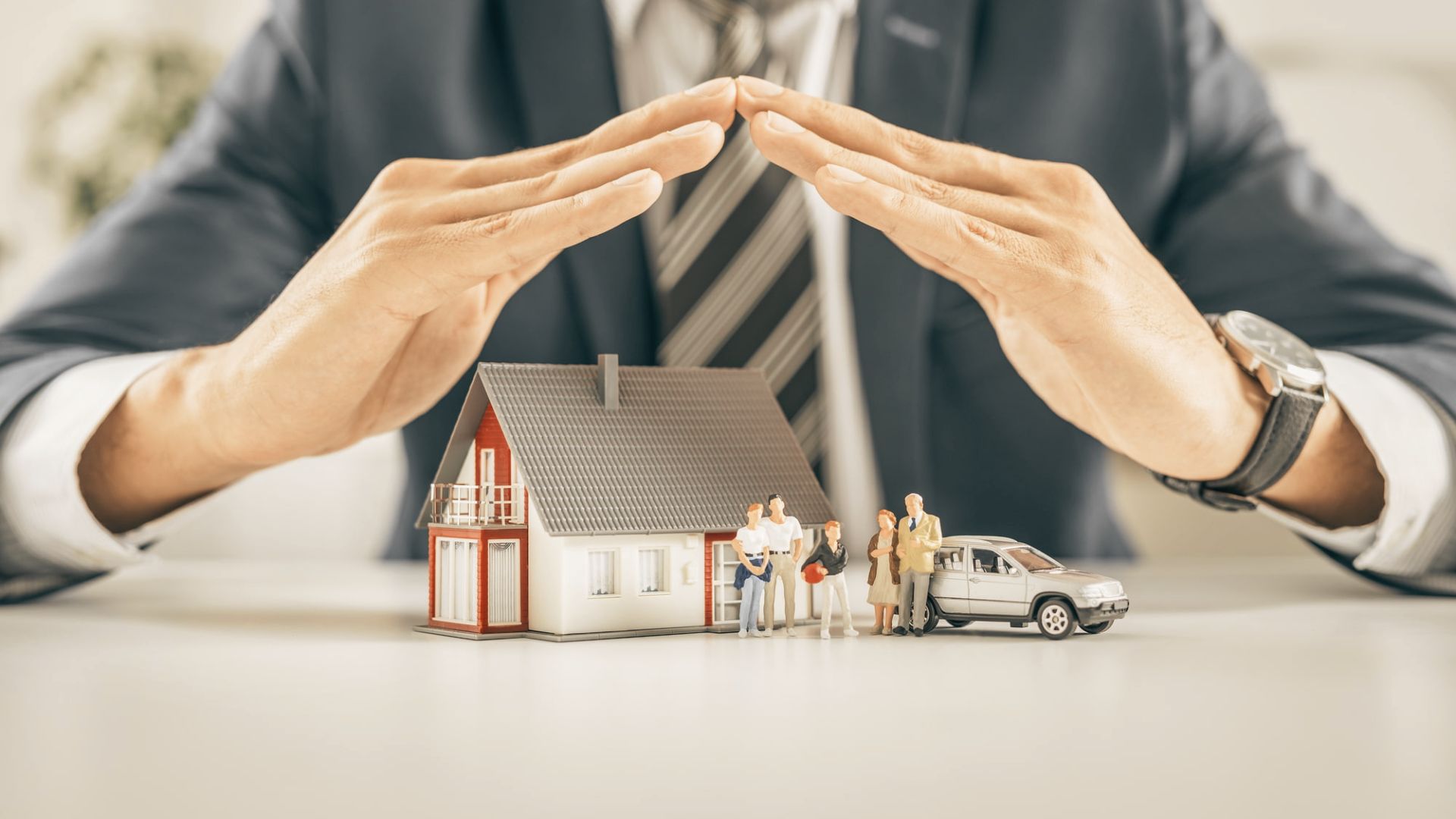 A man in a suit holds a house and a car, symbolizing property ownership and its implications after death.