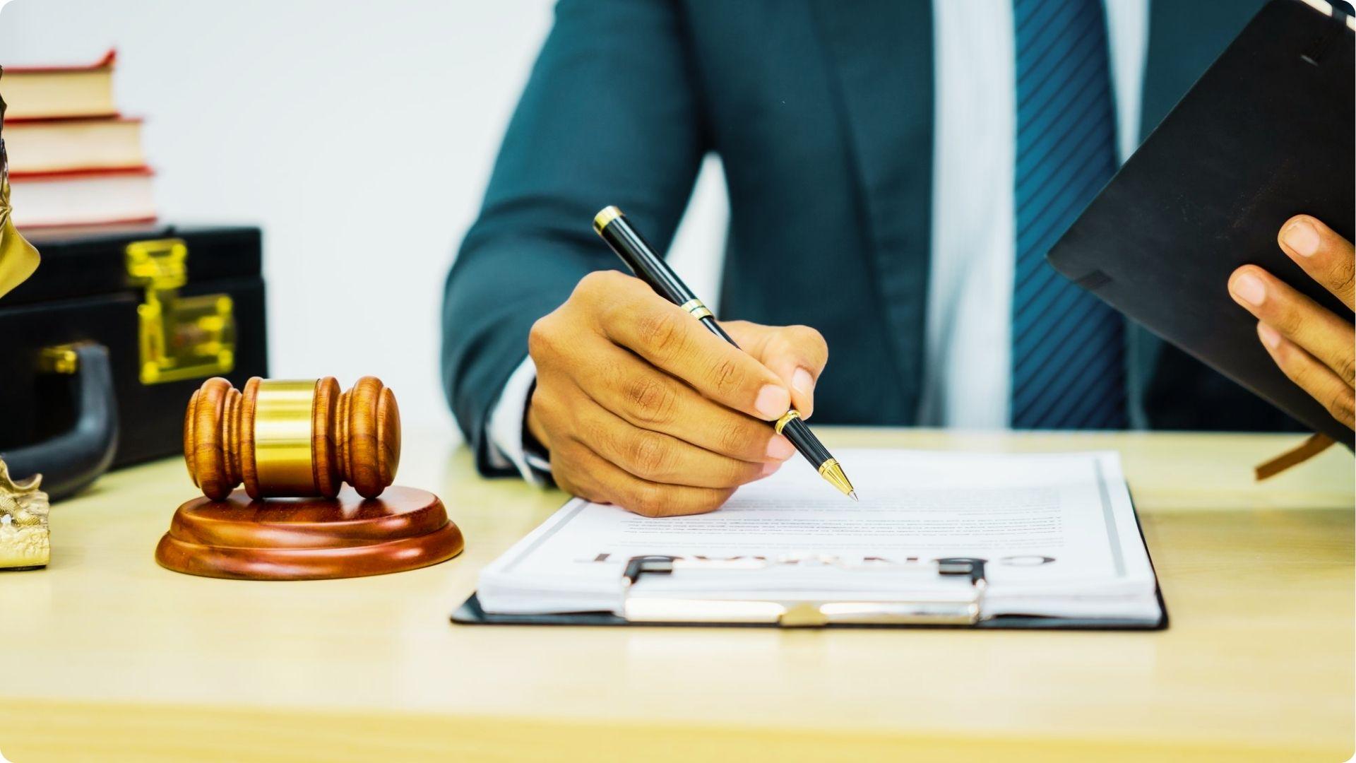 Attorney in a suit reviewing a legal document with a gavel, law books, and briefcase nearby.