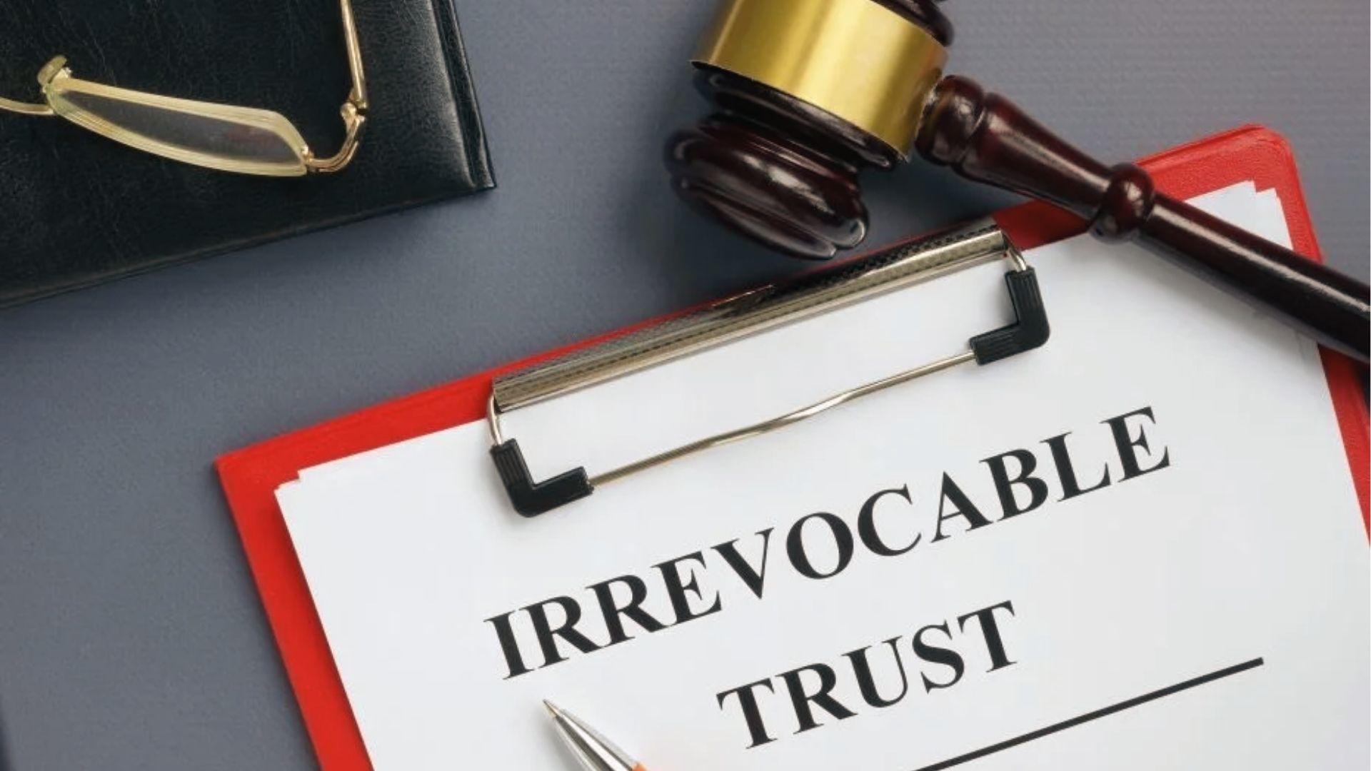 Red clipboard with IRREVOCABLE TRUST form, gavel, and pen showing binding estate planning decisions.