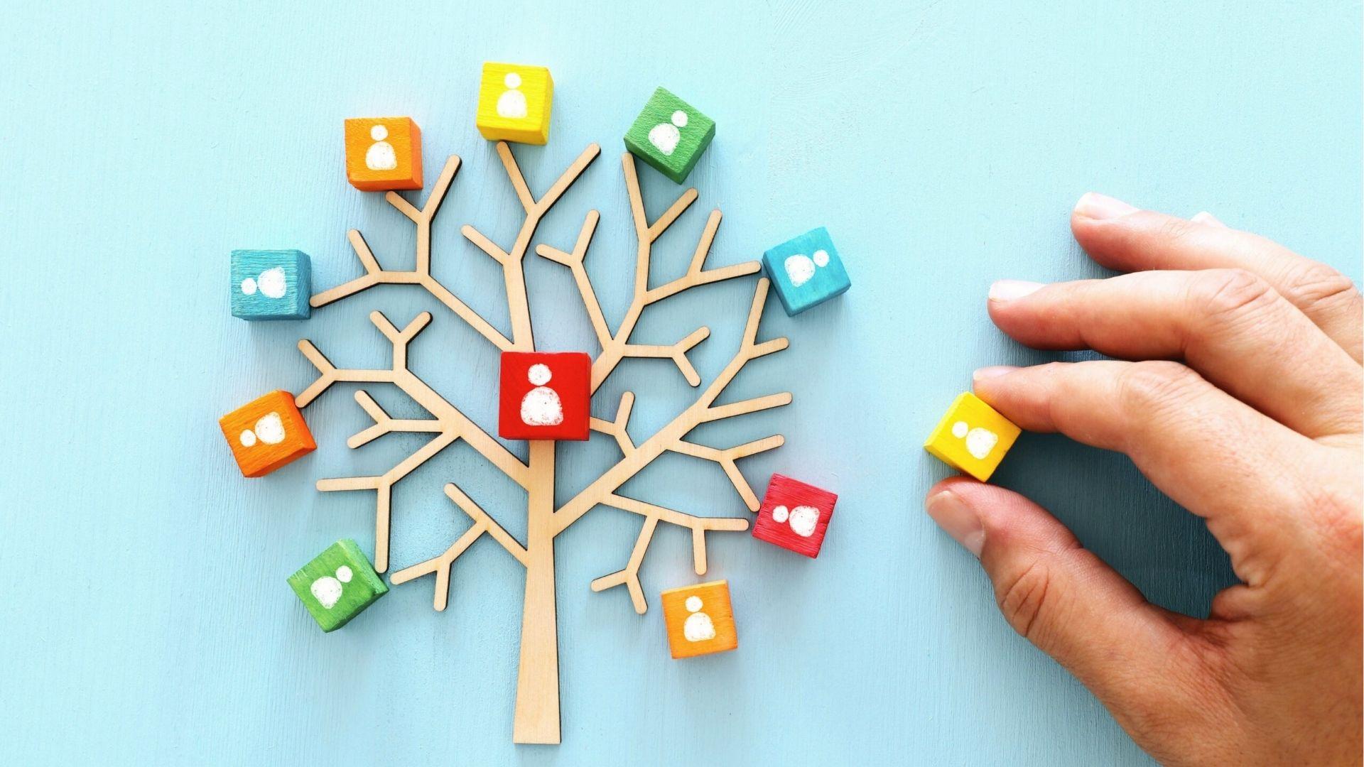 Hand places blocks on the family tree to illustrate descendants' shares in Per Stirpes distribution.