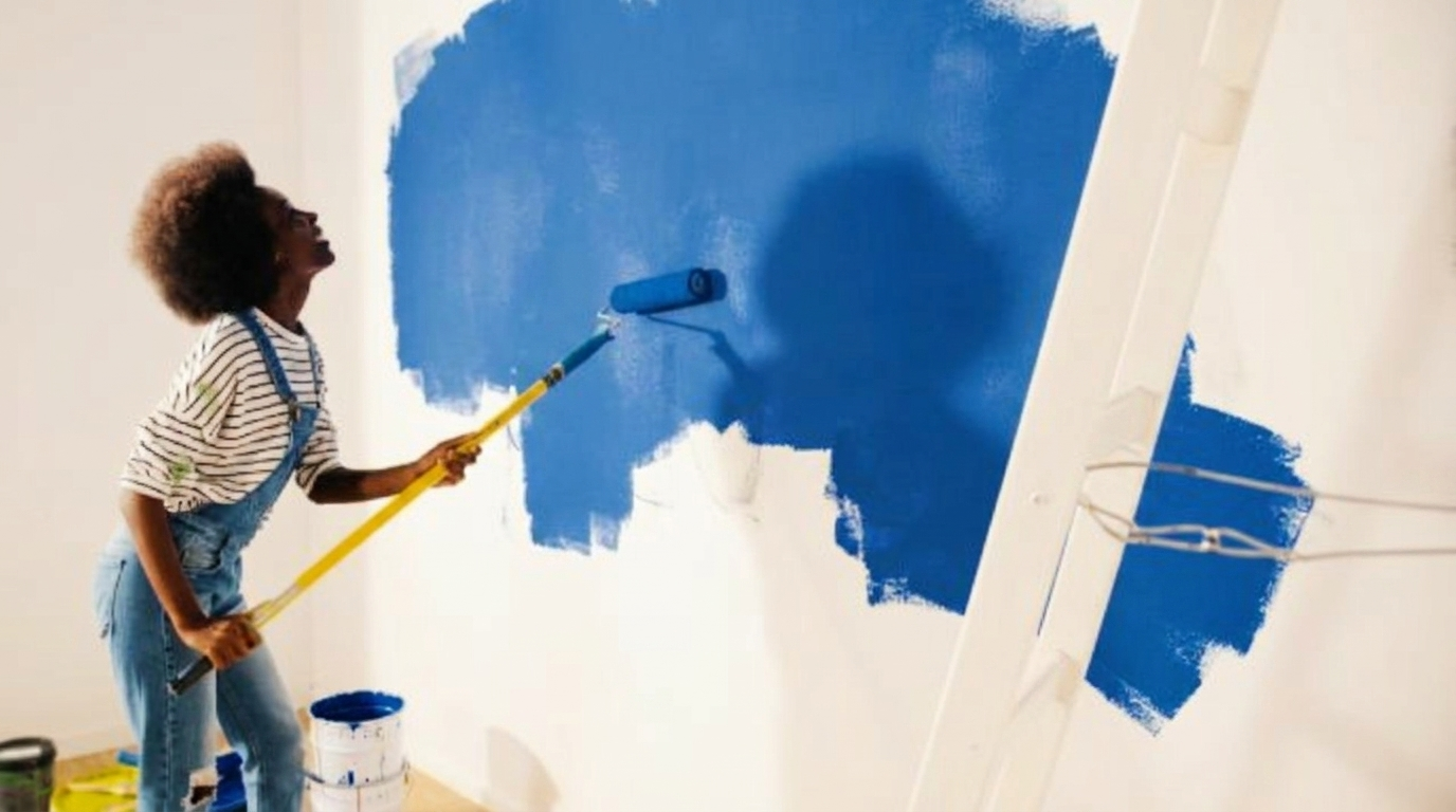 A woman painting a green wall with a roller, illustrating normal wear and tear after three years of use.
