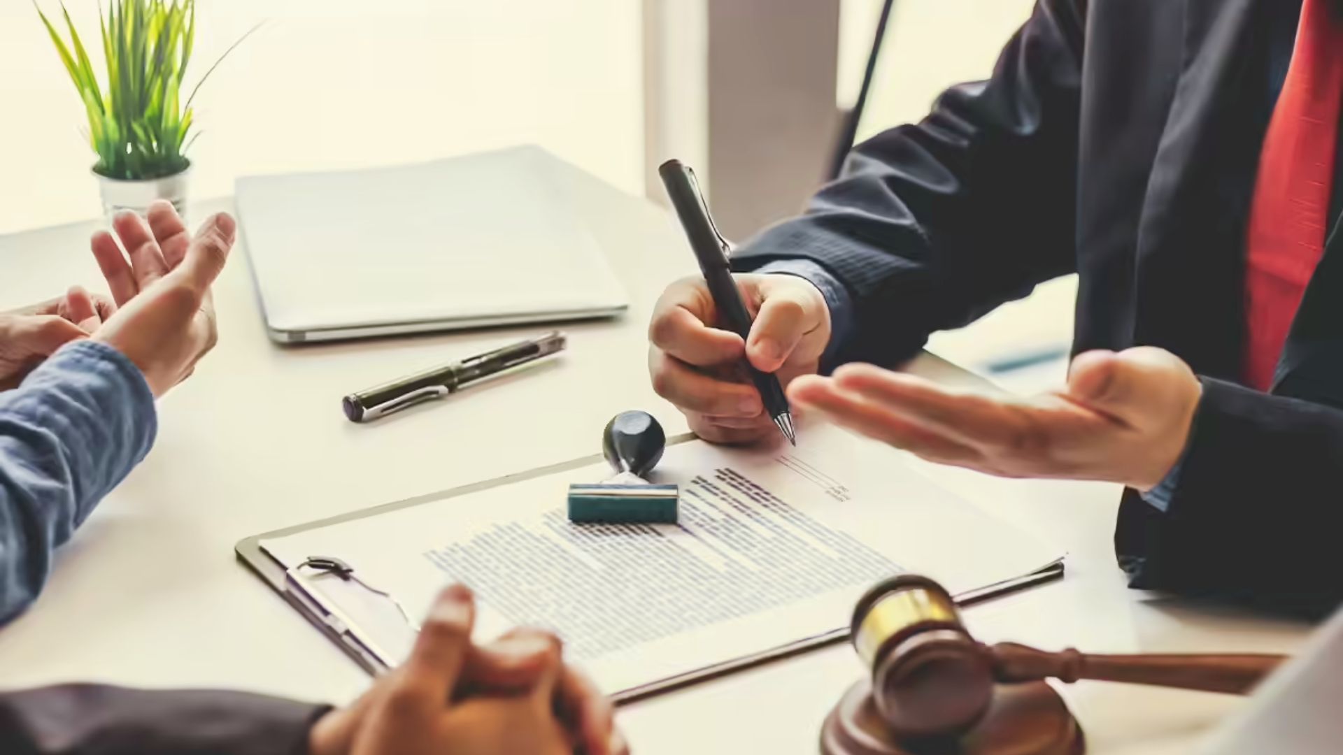 Attorney signing legal documents with heirs present while discussing property sale agreement and inheritance law at office table