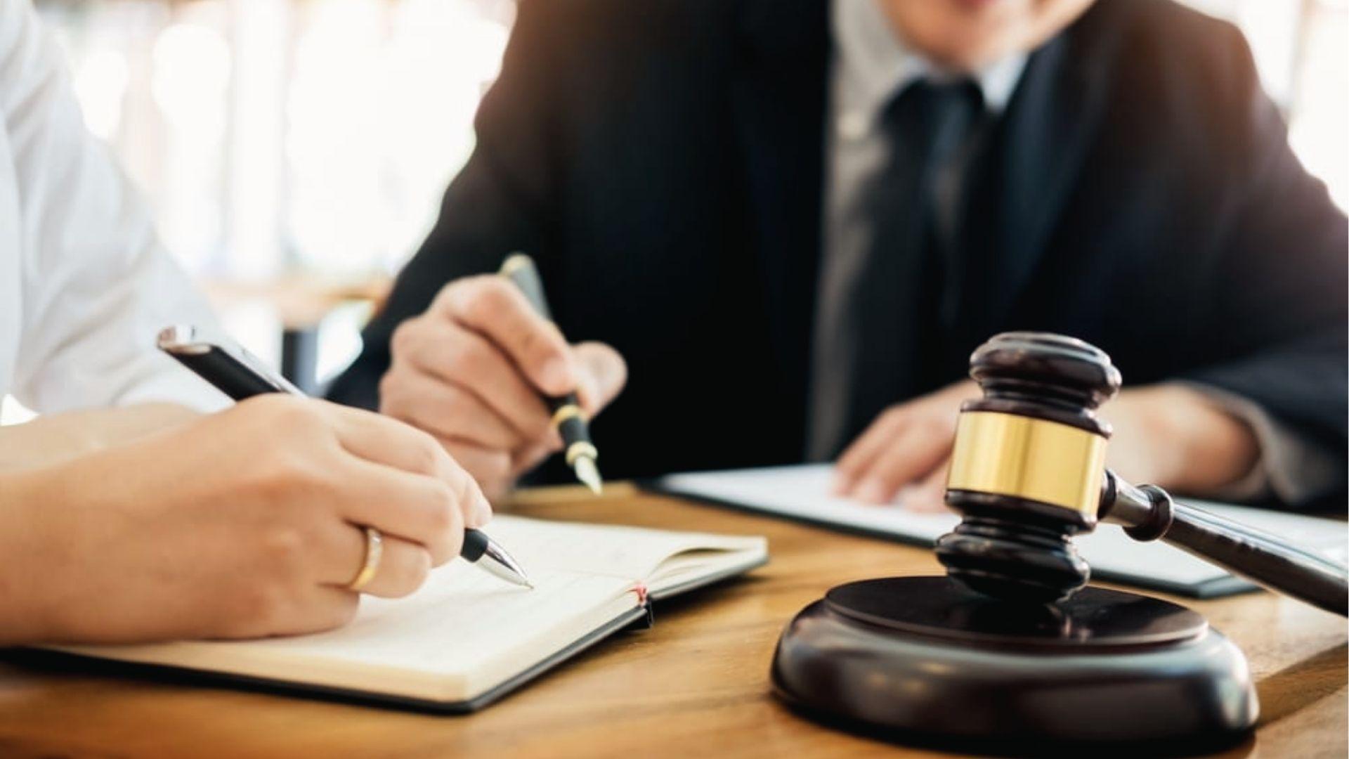 Client and attorney signing documents with gavel, covering legal fees for living trust cost.