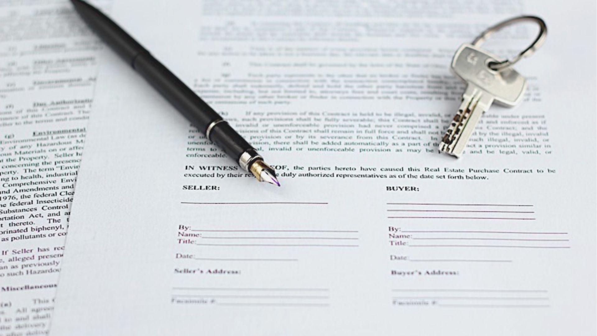 Black fountain pen and metal house keys rest on a signed real estate purchase contract.
