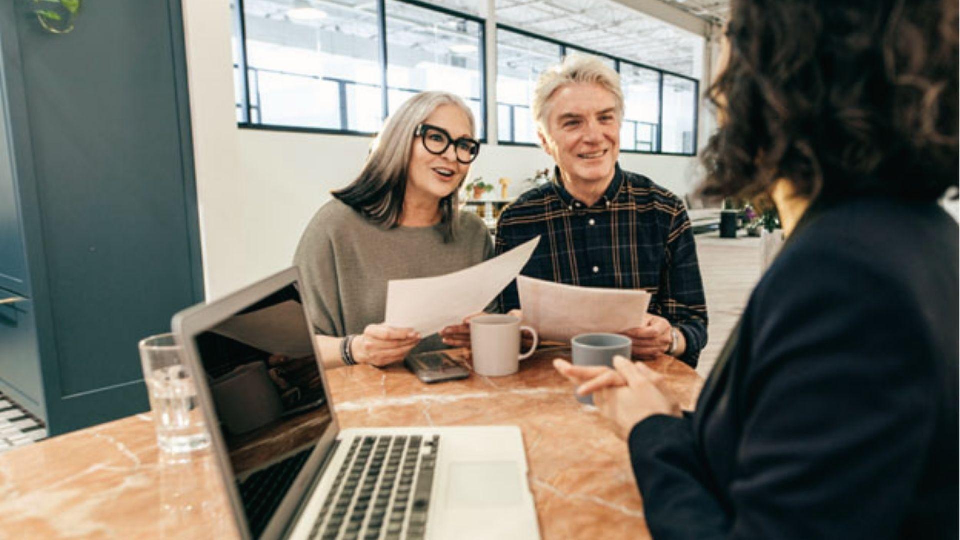 Advisor explains Per Stirpes vs Per Capita inheritance terms to elderly clients over documents.