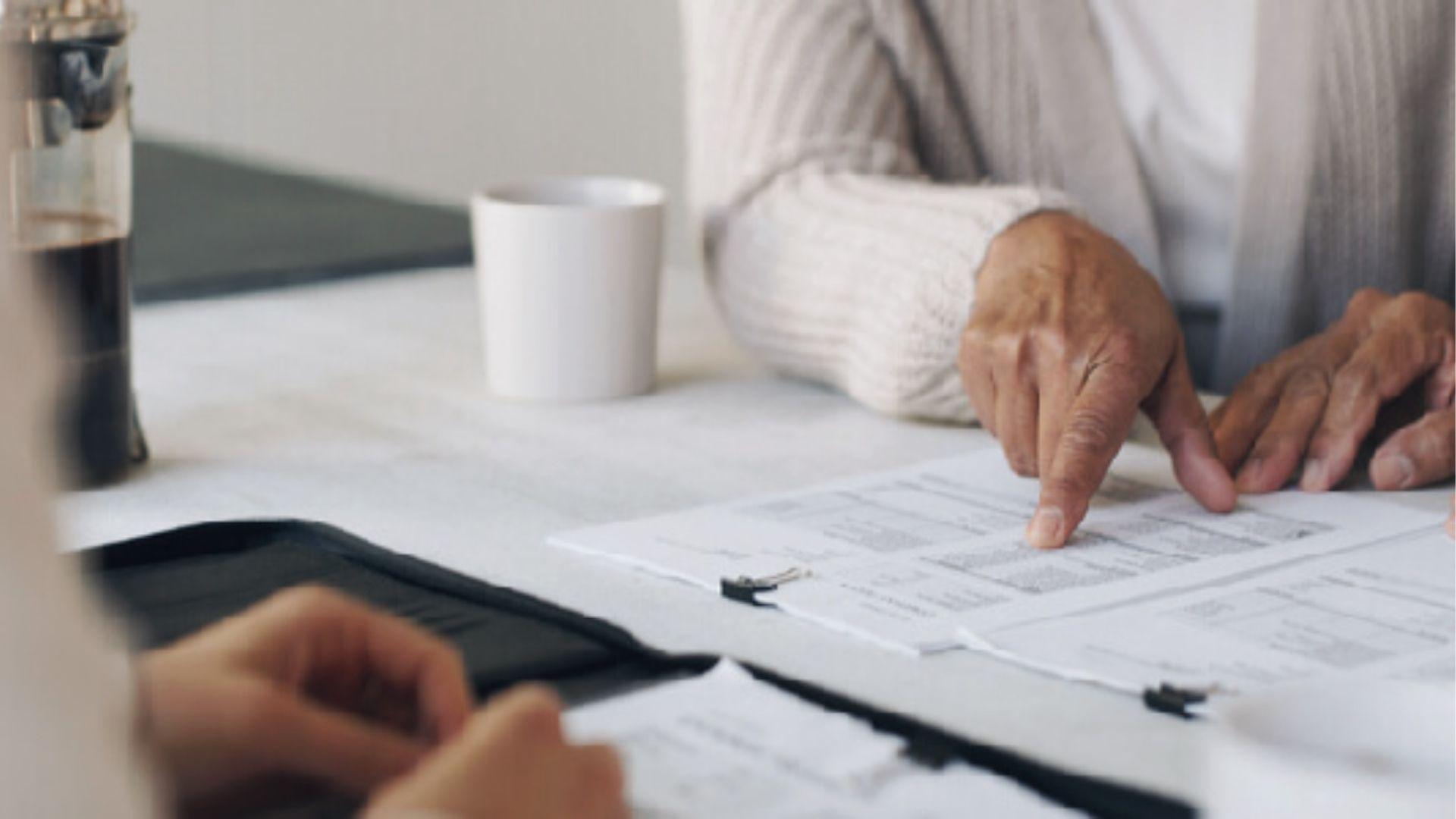 Advisor and senior client point to trust paperwork, weighing irrevocable trust benefits versus loss of control.