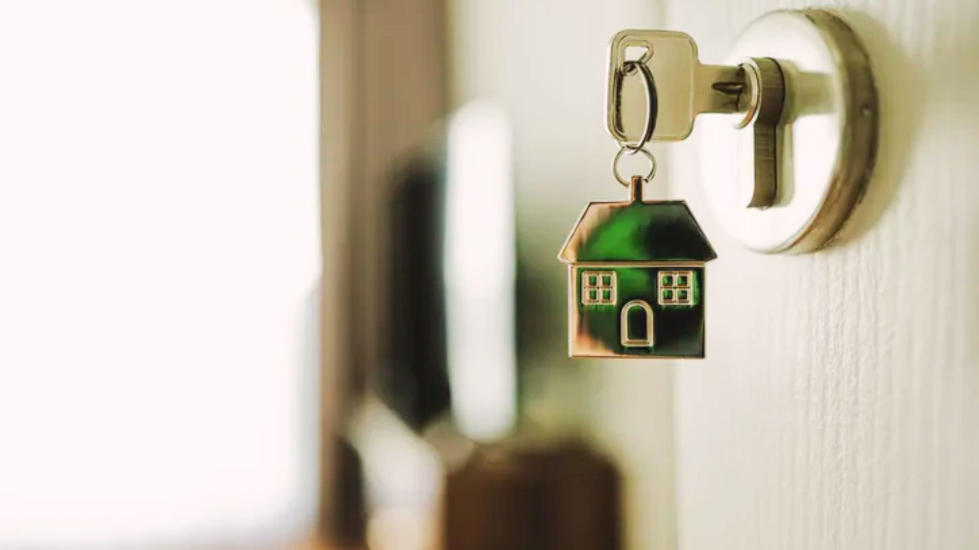 A close-up of a house key dangling from a door handle, representing property access and implications after death