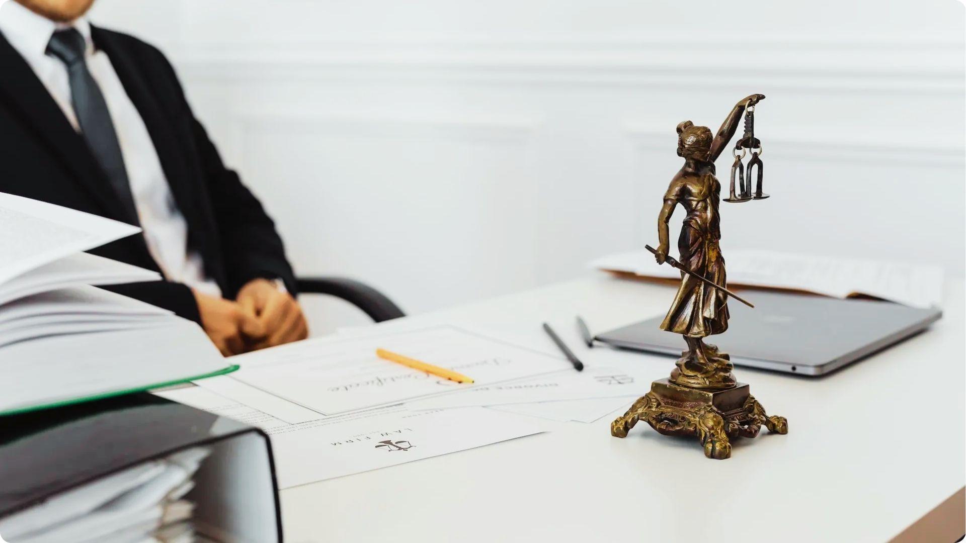 Attorney at a desk with legal documents and a Lady Justice statue, reviewing tenant rights.