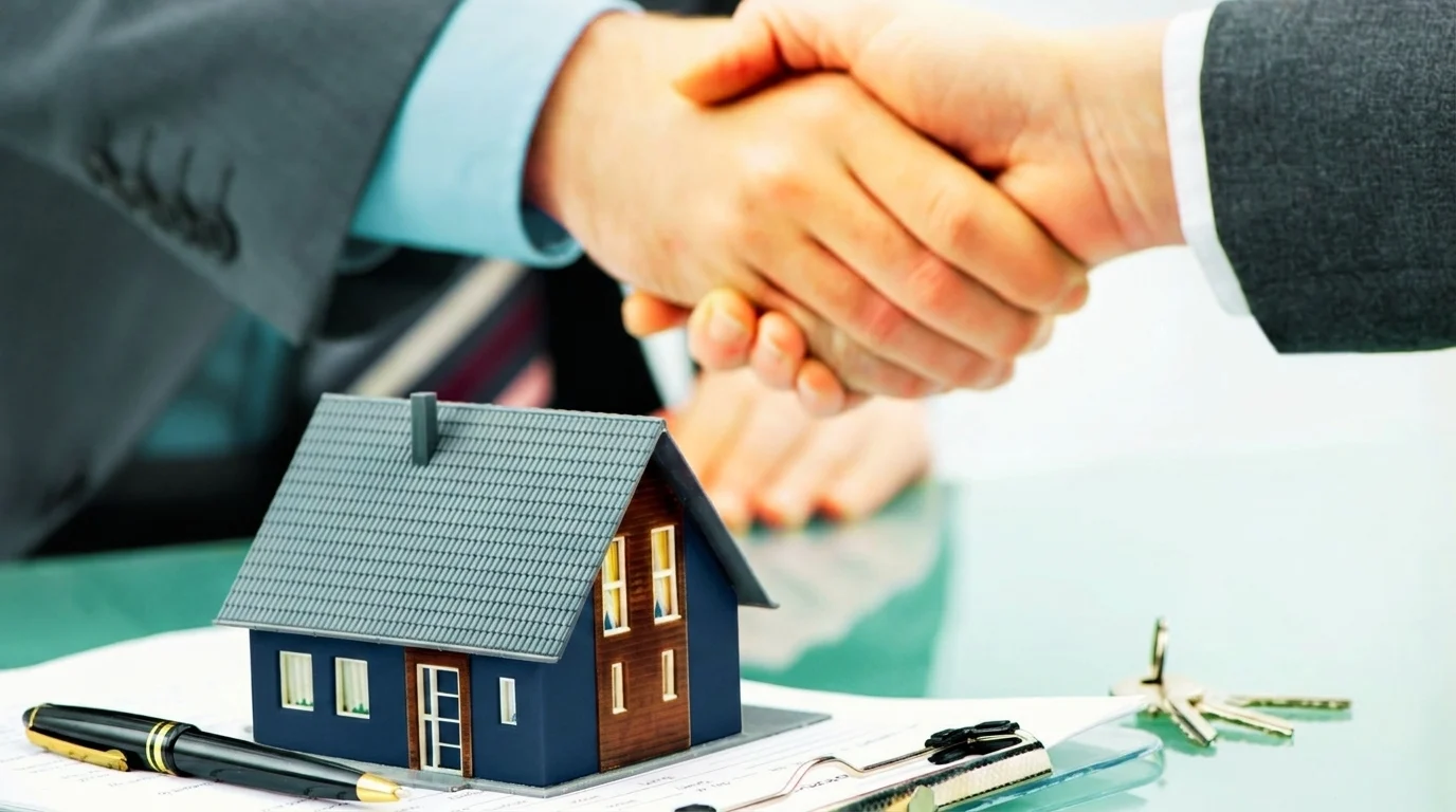 Two individuals shaking hands over a model house, symbolizing agreement on Section 8 housing rental terms.