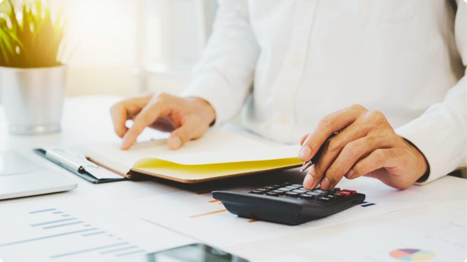 Person calculating finances over property documents and charts.