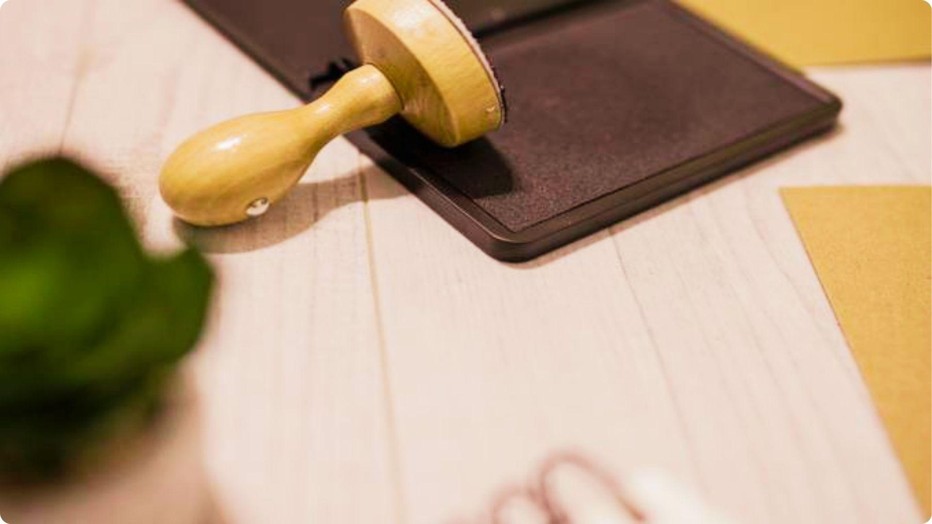 Close-up of a rubber stamp and ink pad next to legal papers.