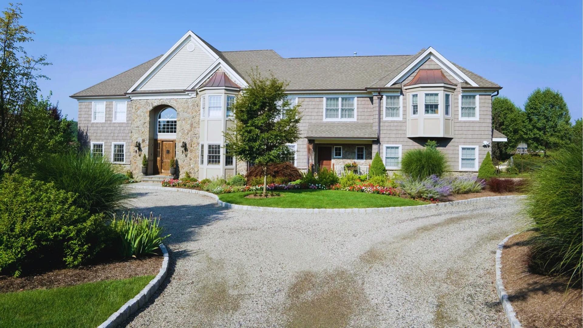 Large stone and shingle house with circular gravel driveway and landscaped island, illustrating private driveway with no shared easement.