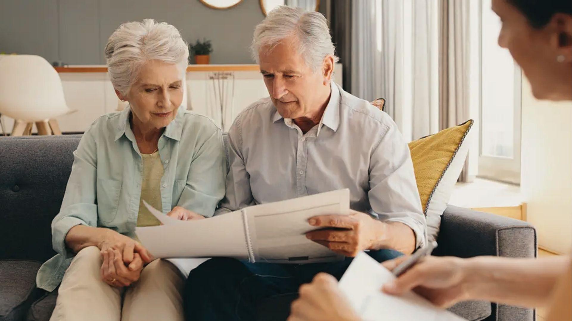 Elderly pair reviews living trust vs will paperwork with consultant to decide on asset transfer.