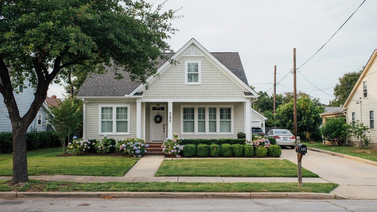 Cottage style house with front porch, flowers, and driveway car parked.
