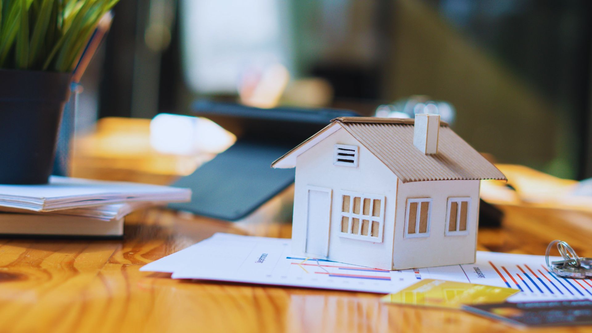 A close-up of a hand holding a house key, with displaying home buying resources.
