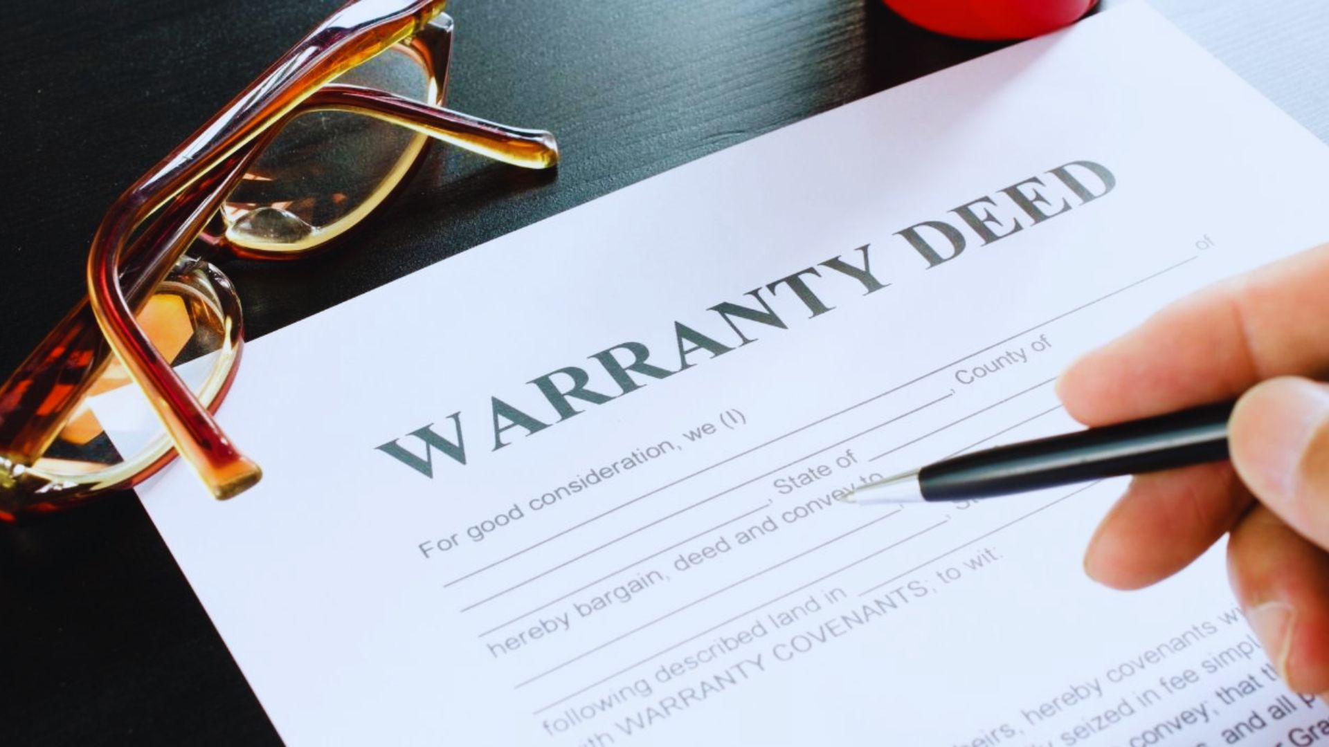 Signed warranty deed document with house keys on a wooden table.