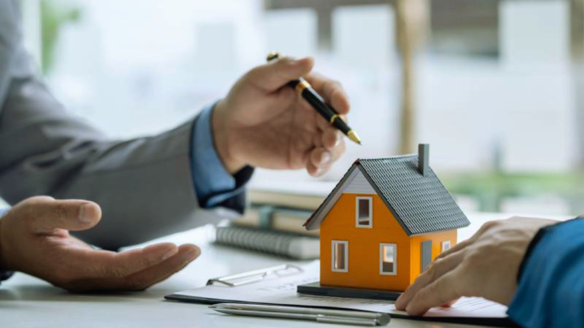 Businessman explaining house model to client over contract, real estate consultation and home purchase