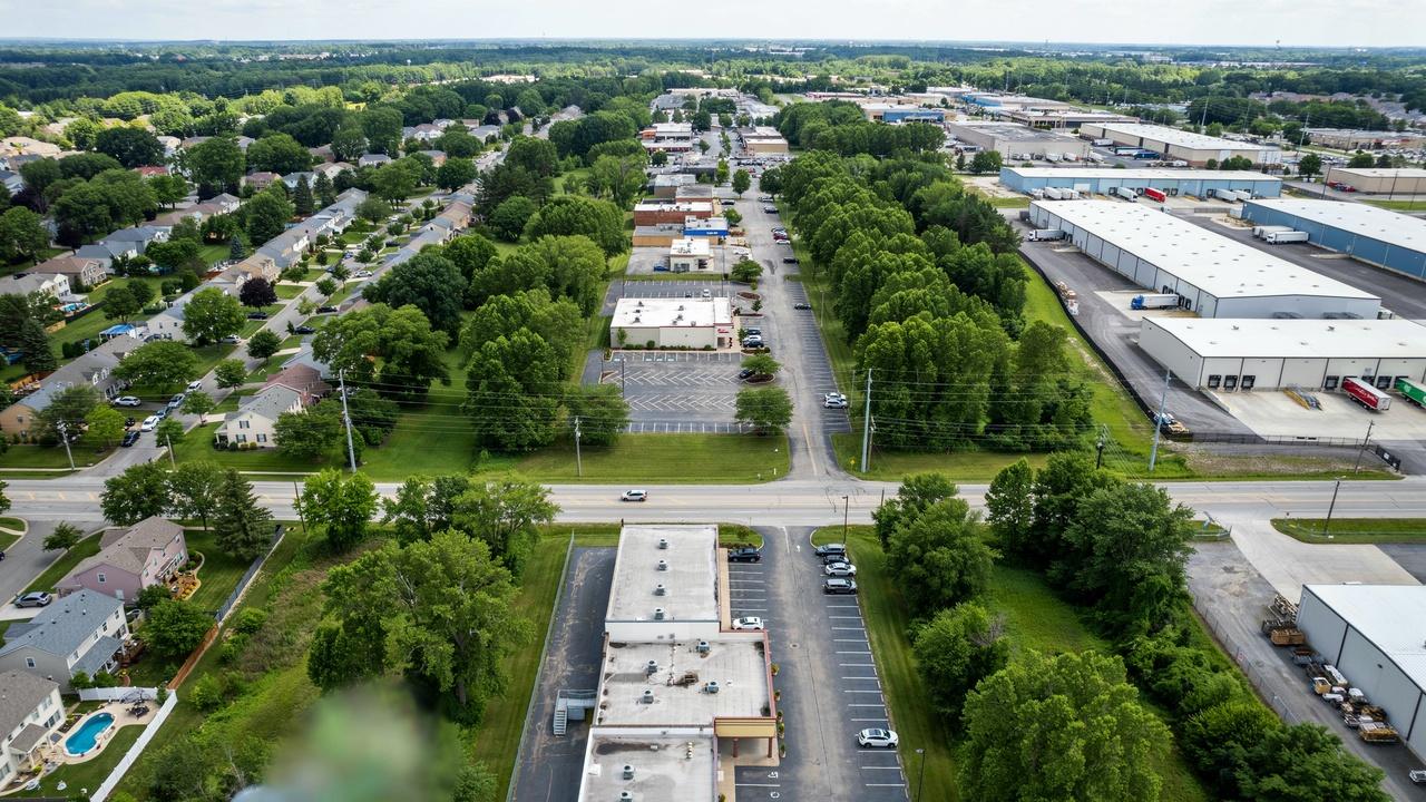 Landscaped buffer zone separating residential and commercial areas with trees and open green space.