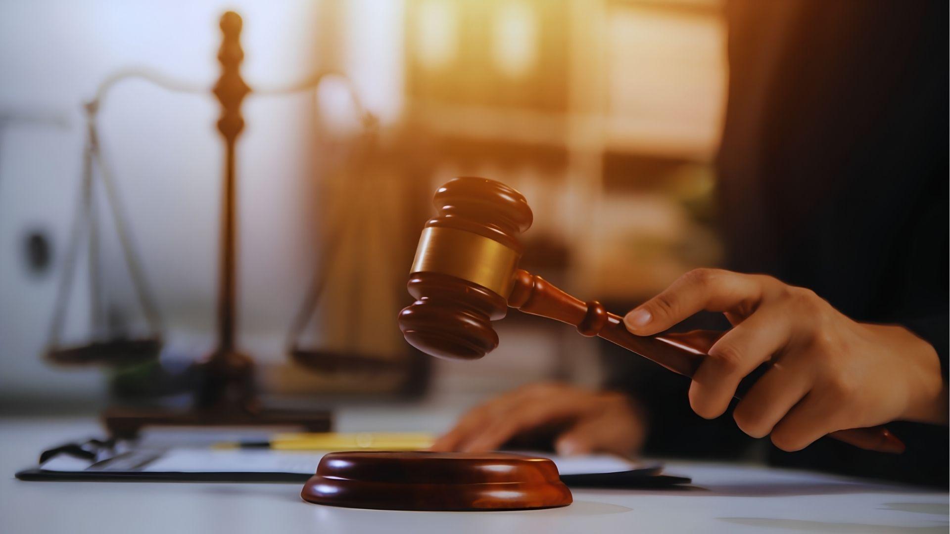 Judge's gavel striking a block beside scales of justice in a law office
