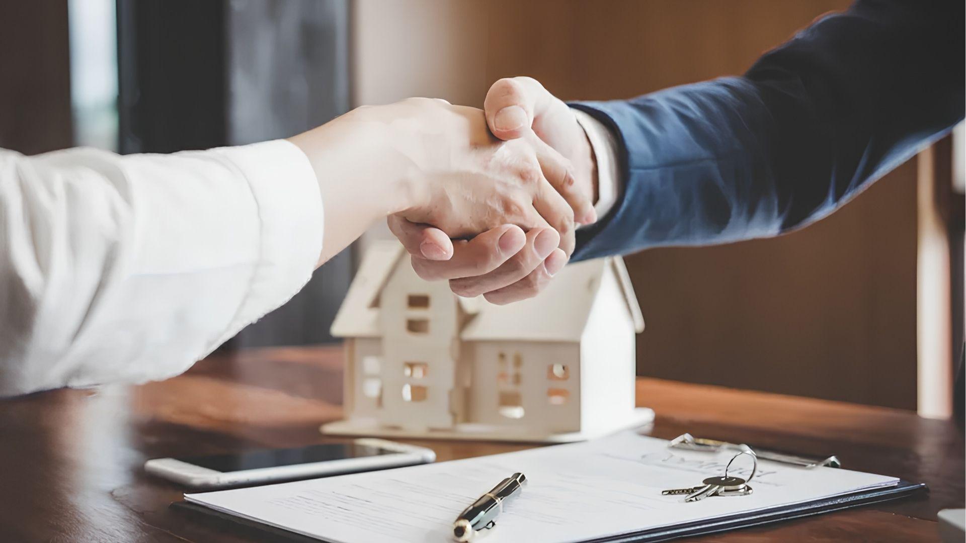 Buyer and real estate agent shaking hands after closing a home purchase.