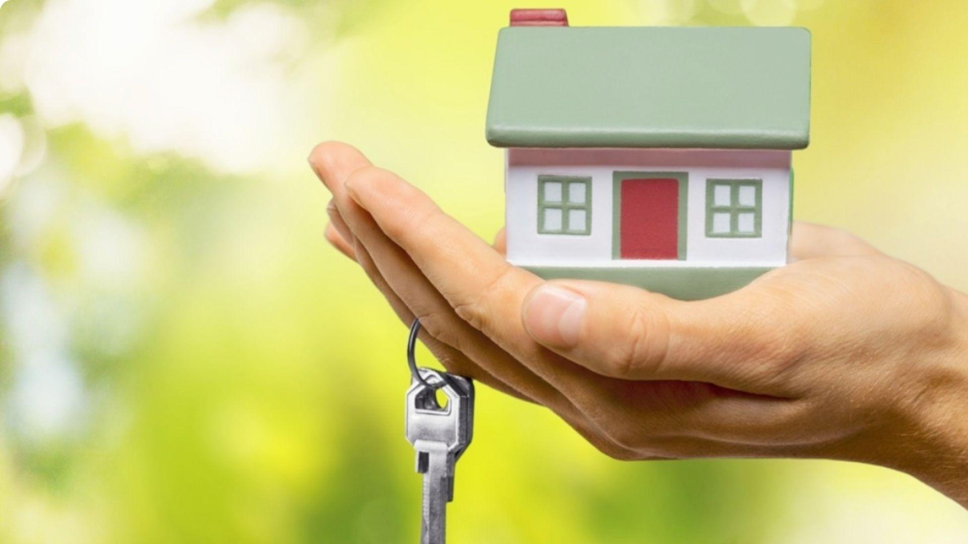 Hand holding small model house with key symbolizing individual sole property ownership