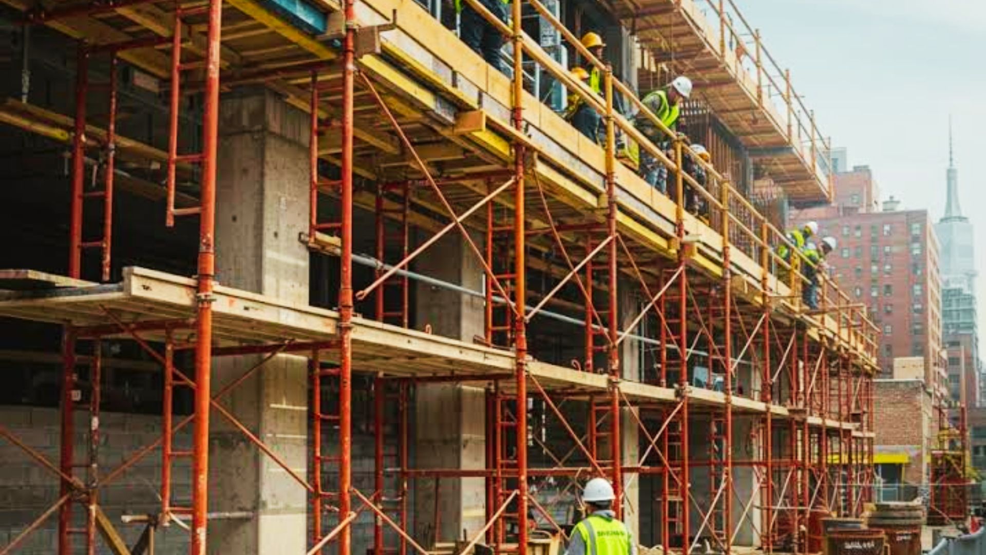 A group of construction workers on scaffolding, performing tasks on a building in New York City.