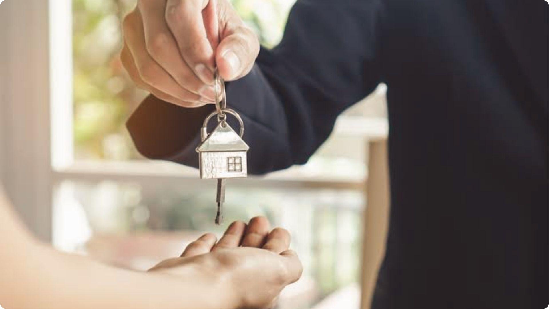 Landlord handing house-shaped keys to tenants after discussing property safety and injury liability.