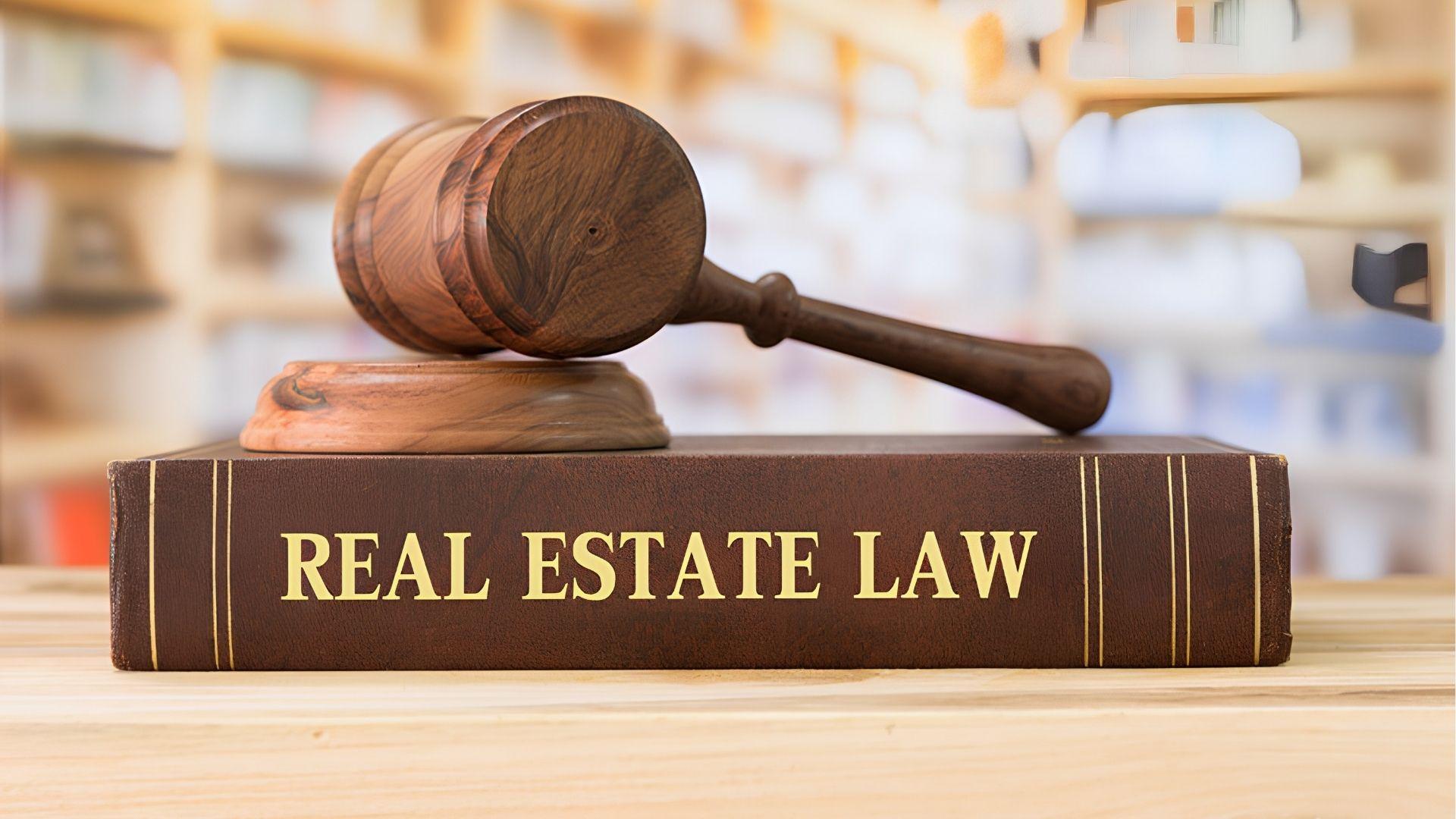 Wooden gavel resting on a Real Estate Law book in a library