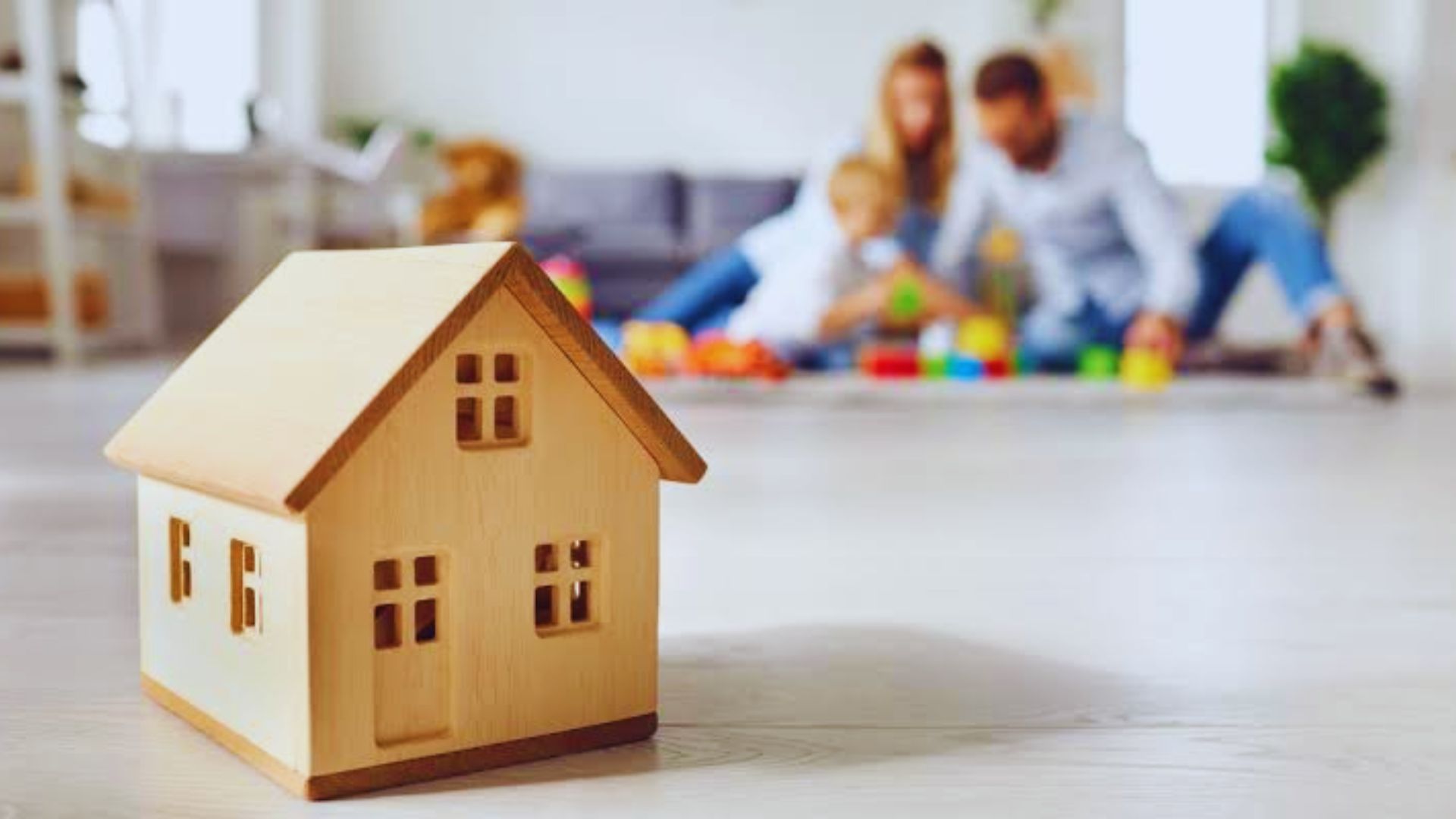 A family stands around a wooden house model on the floor, contemplating ways to avoid capital gains tax on inherited property.