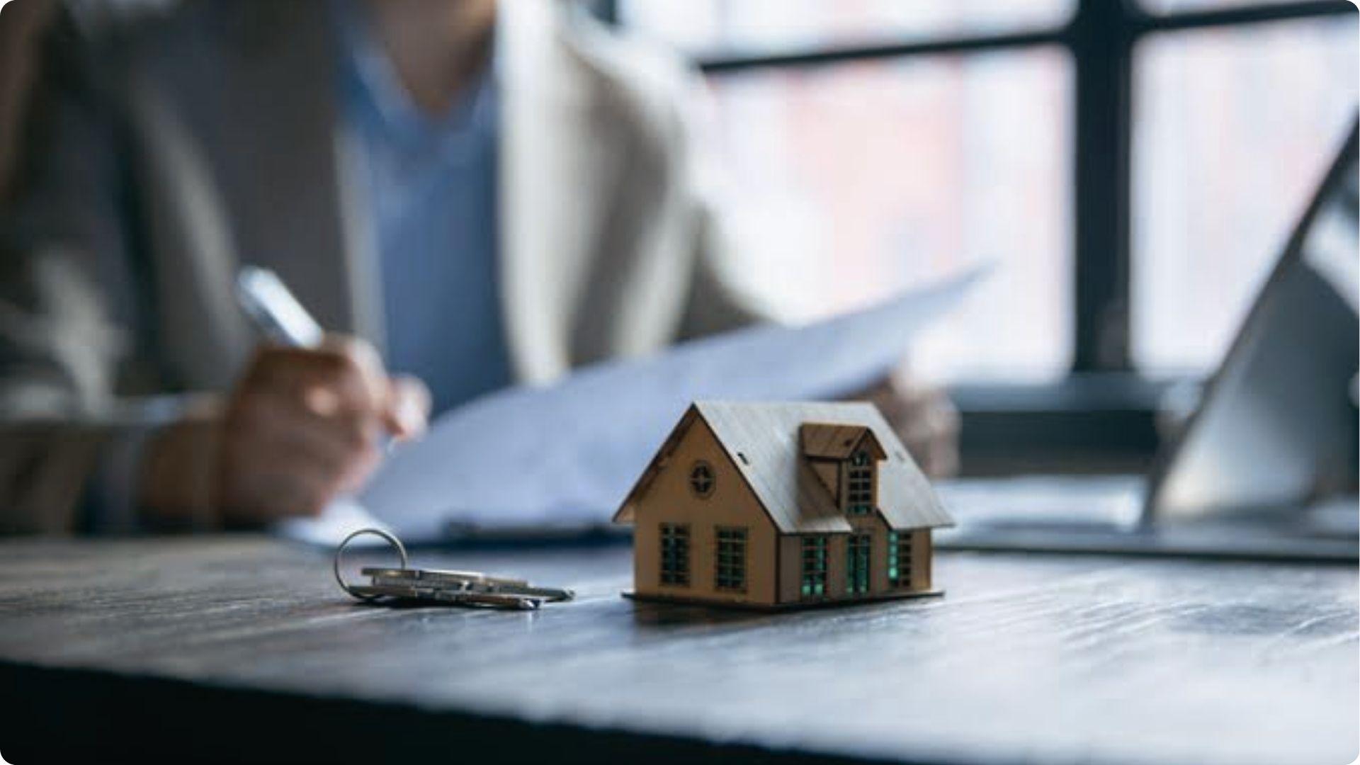 Mini house model with keys as owner reviews papers to appeal overvalued property tax assessment