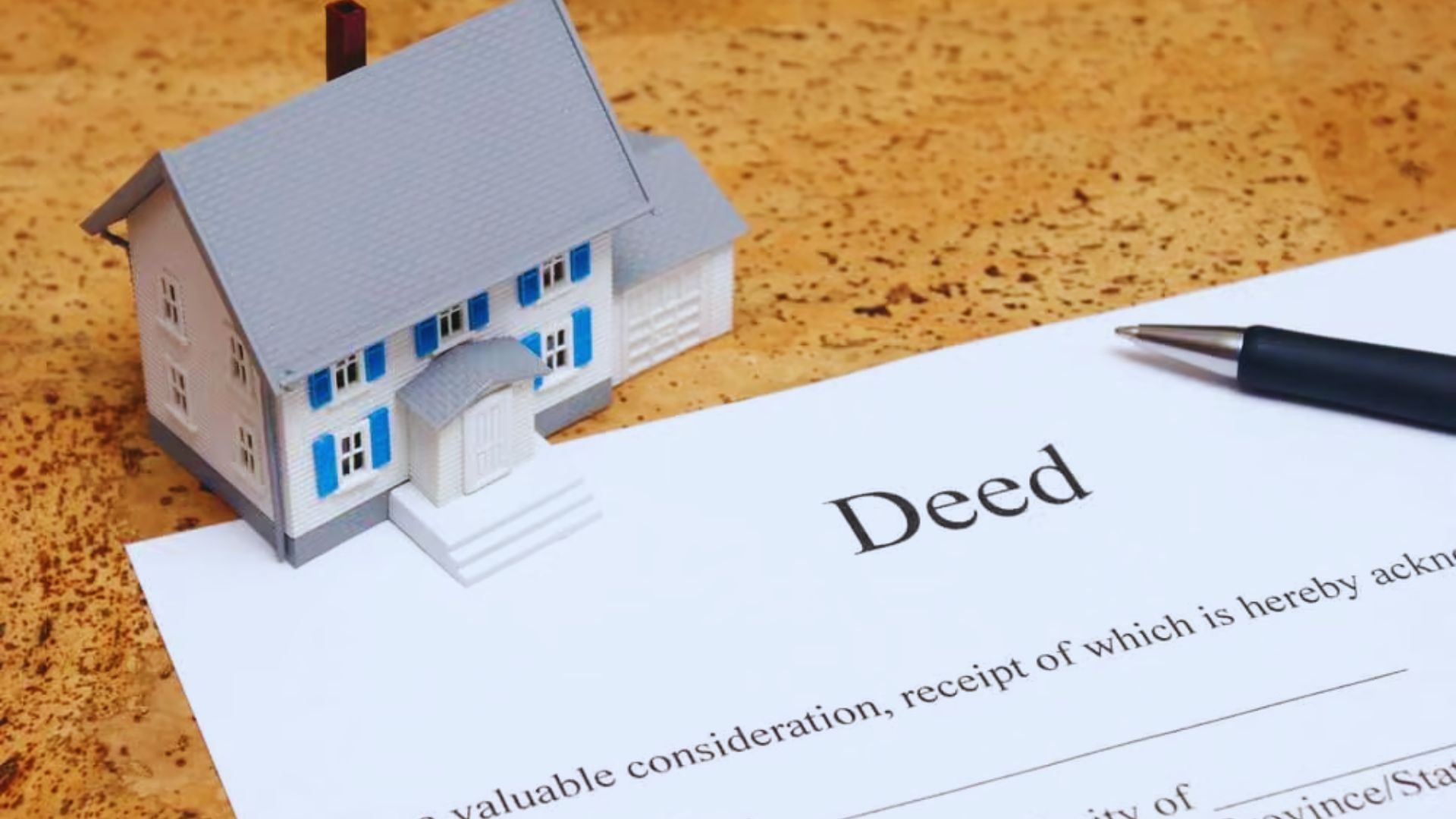 a property deed with a pen, contemplating legal steps to remove a name.