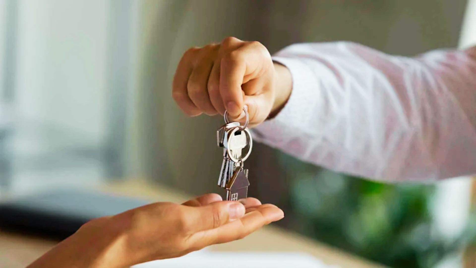 A person handing over a key to another, symbolizing the transfer of property in a reverse mortgage transaction.