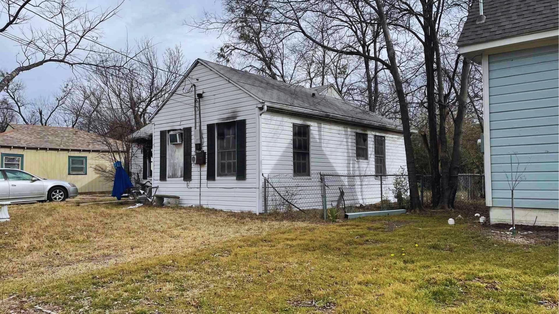 Abandoned white house with overgrown yard showing potential foreclosure distressed property needing repair and maintenance.