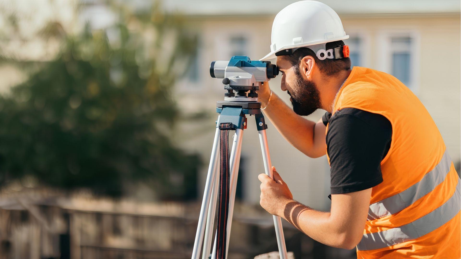 Surveyor using a leveling instrument to measure residential property land.