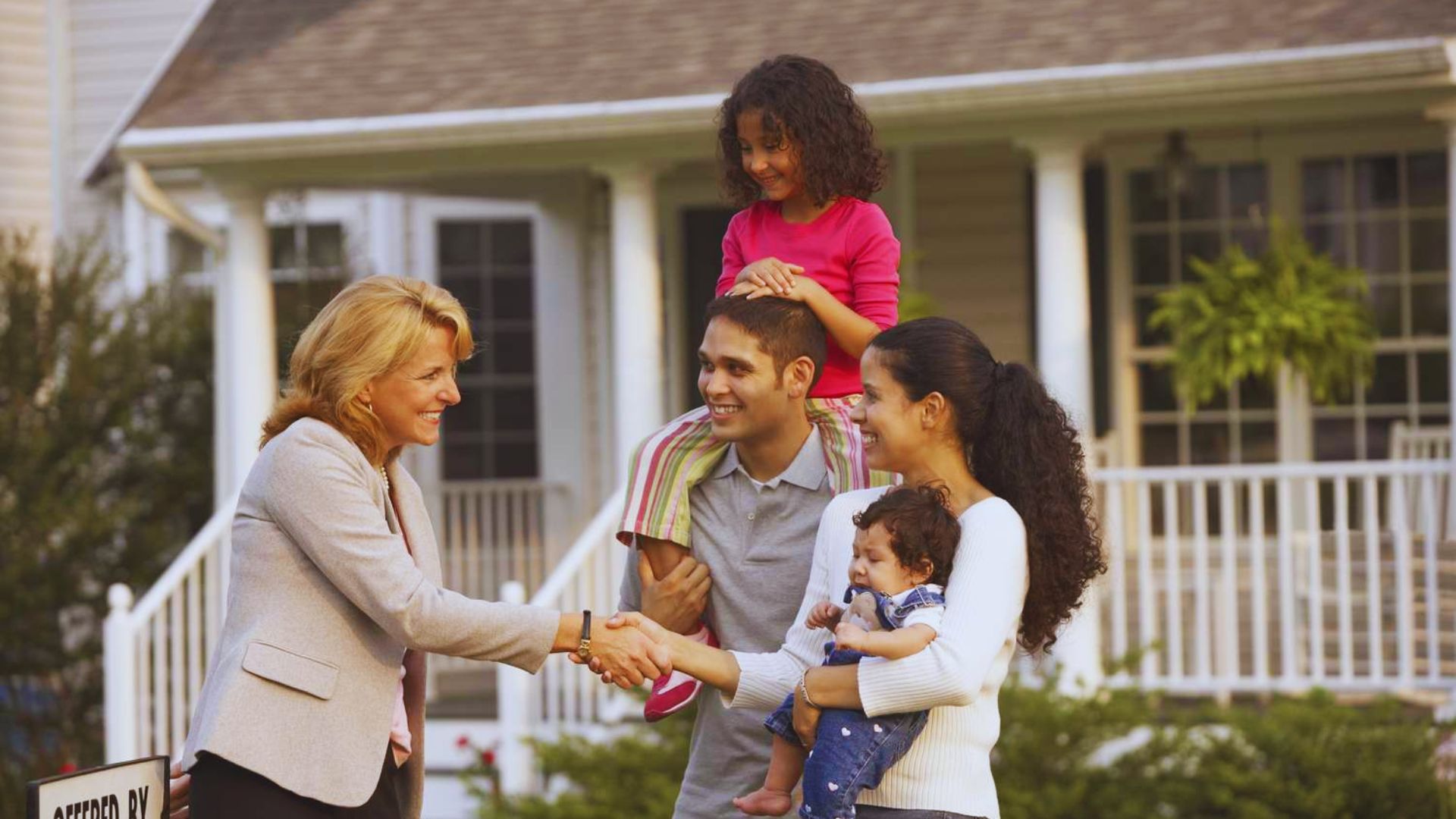 A family shaking hands in front of a house, symbolizing a discussion about inherited property and tax strategies.