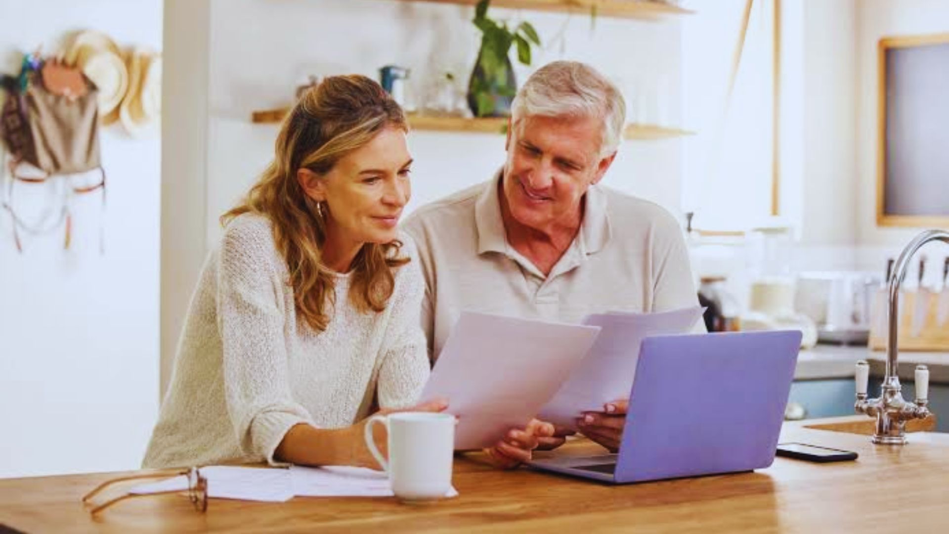 A man and woman at a table reviewing documents on a laptop discussing deed costs.